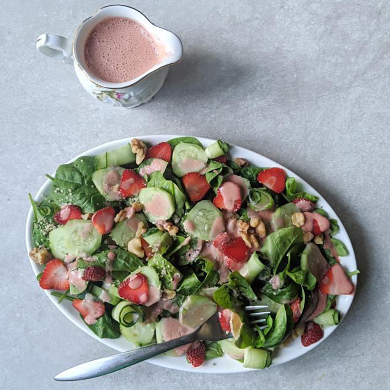 Colorful healthy salad dressing recipe using strawberries, shown on a summer salad