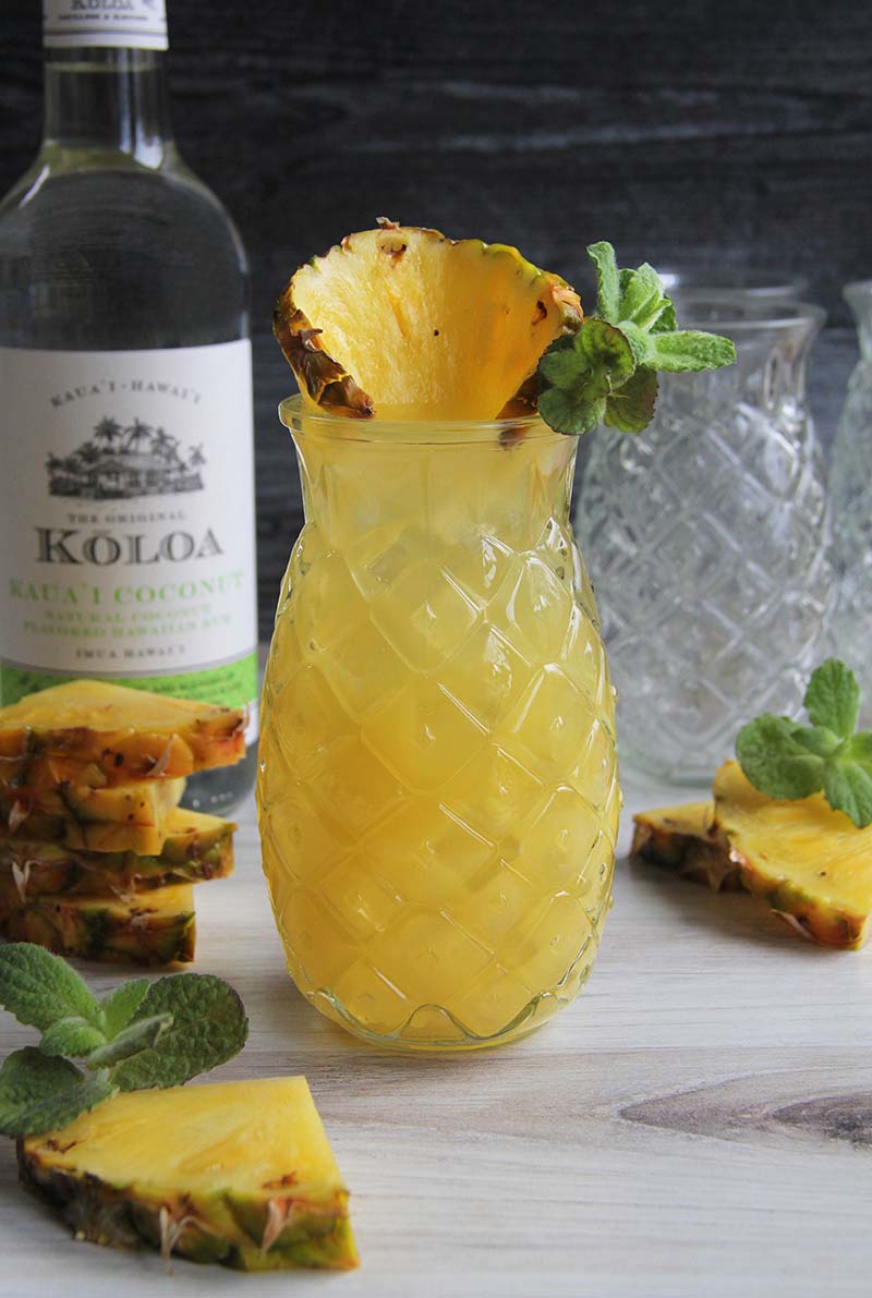 Three-ingredient Pineapple Coconut Rum Fizz cocktail, shown with a bottle of Koloa Rum Coconut Rum.