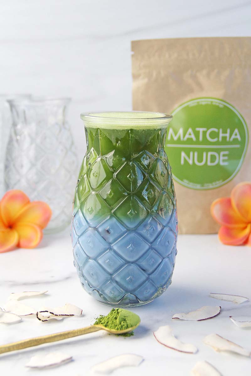 Blue coconut matcha latte, shown next to a bag of Matcha Nude matcha.
