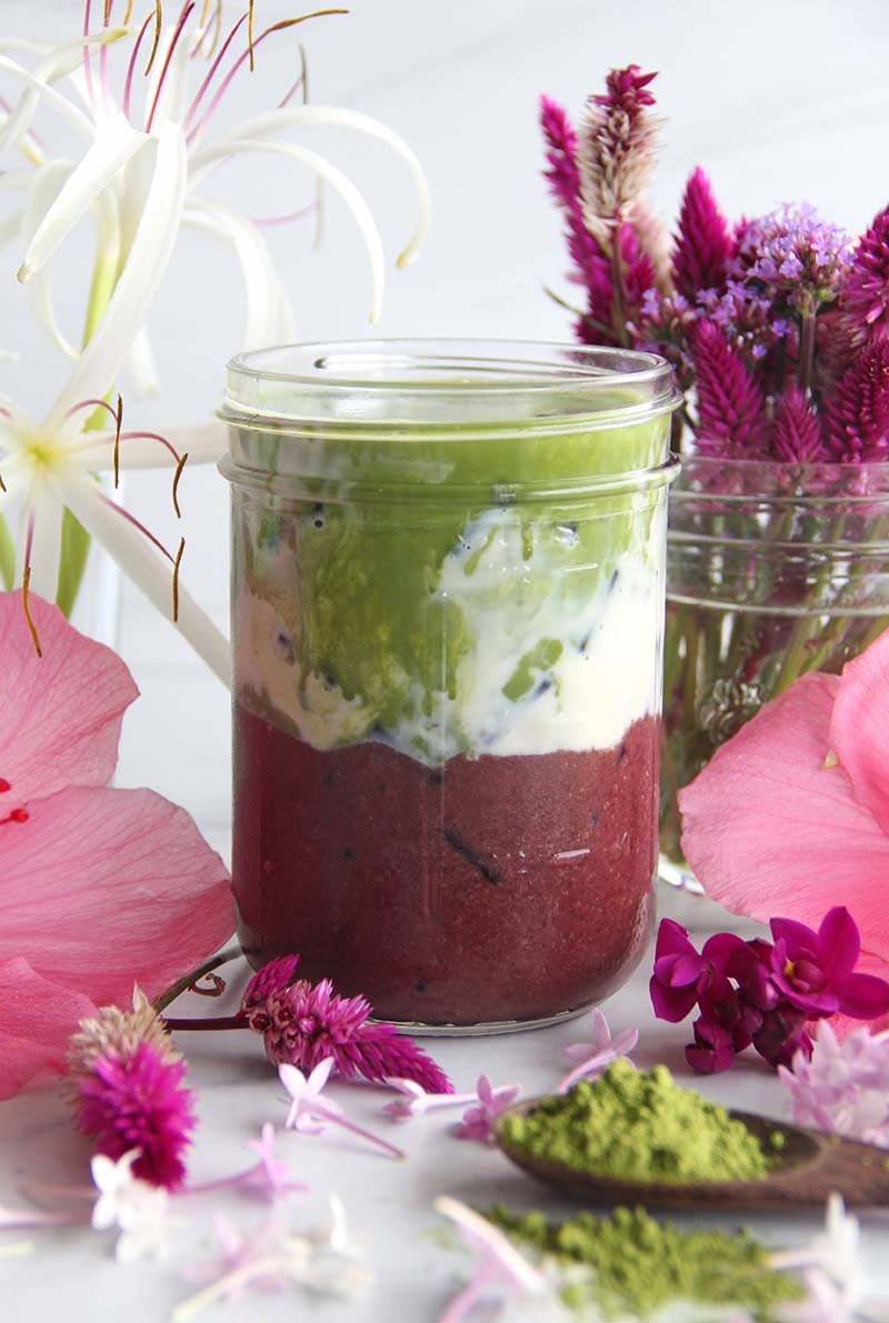 Close-up of a Iced Açaí Matcha Latte, showing purple (acai), white (milk), and green (matcha) layers.
