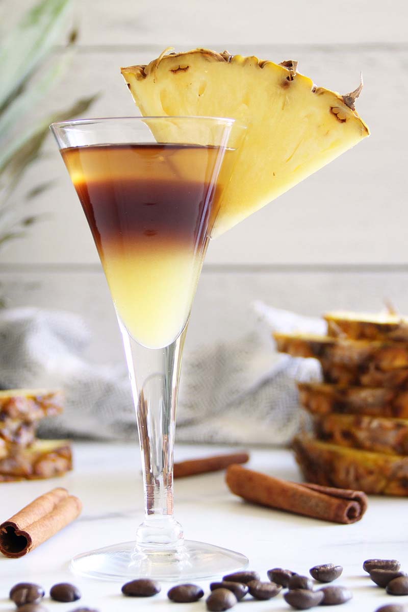 Pineapple Express rum cocktail made with Koloa Spice Rum and Koloa Coffee Rum, shown in a white kitchen with a pineapple slice garnish.