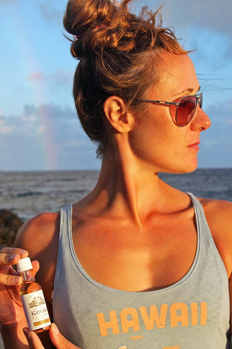The blogger holding a small bottle of Koloa Rum on the beach in Hawaii.