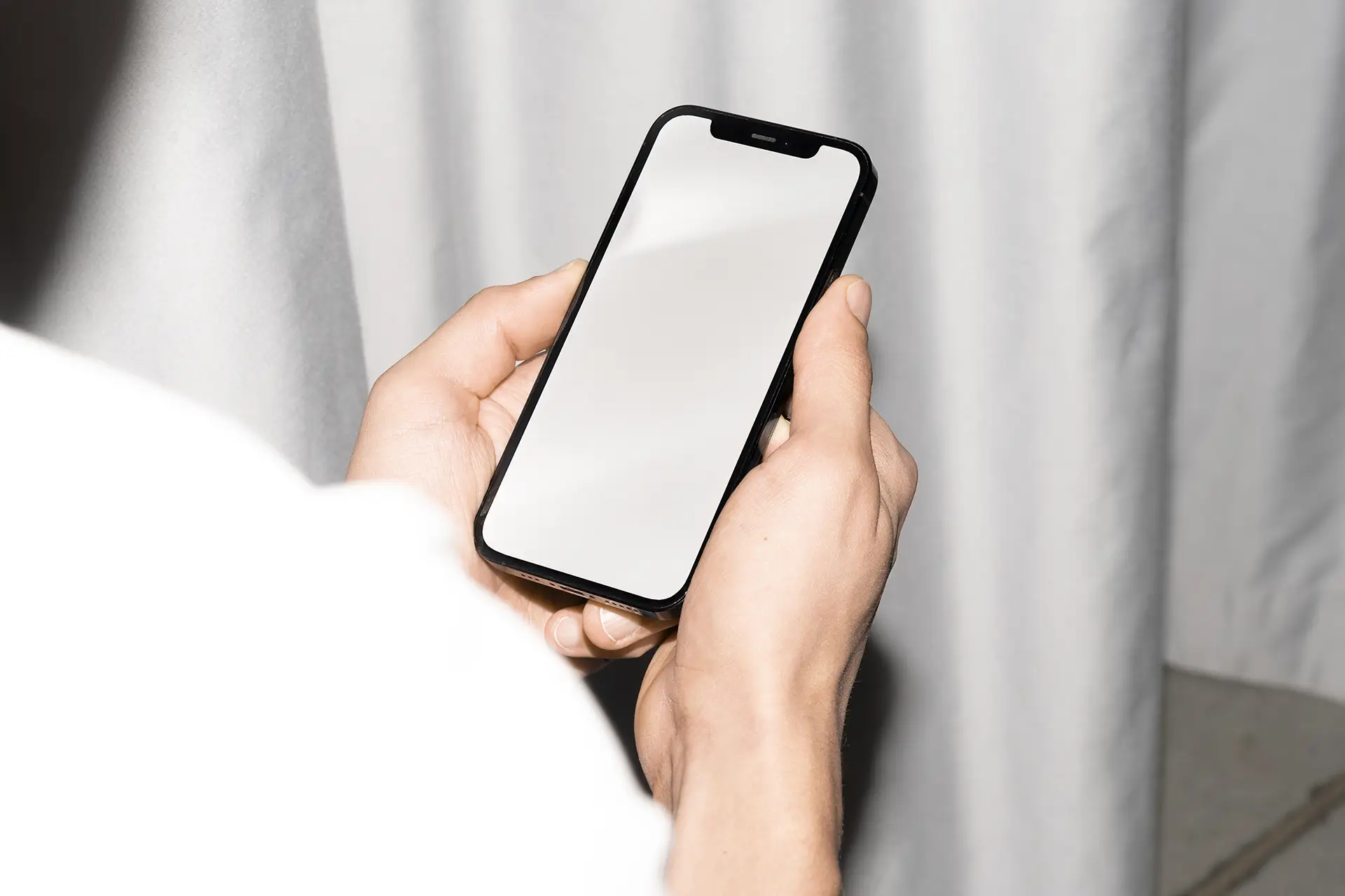 Blank iPhone Mockup held in both hands against a neutral background for app display.