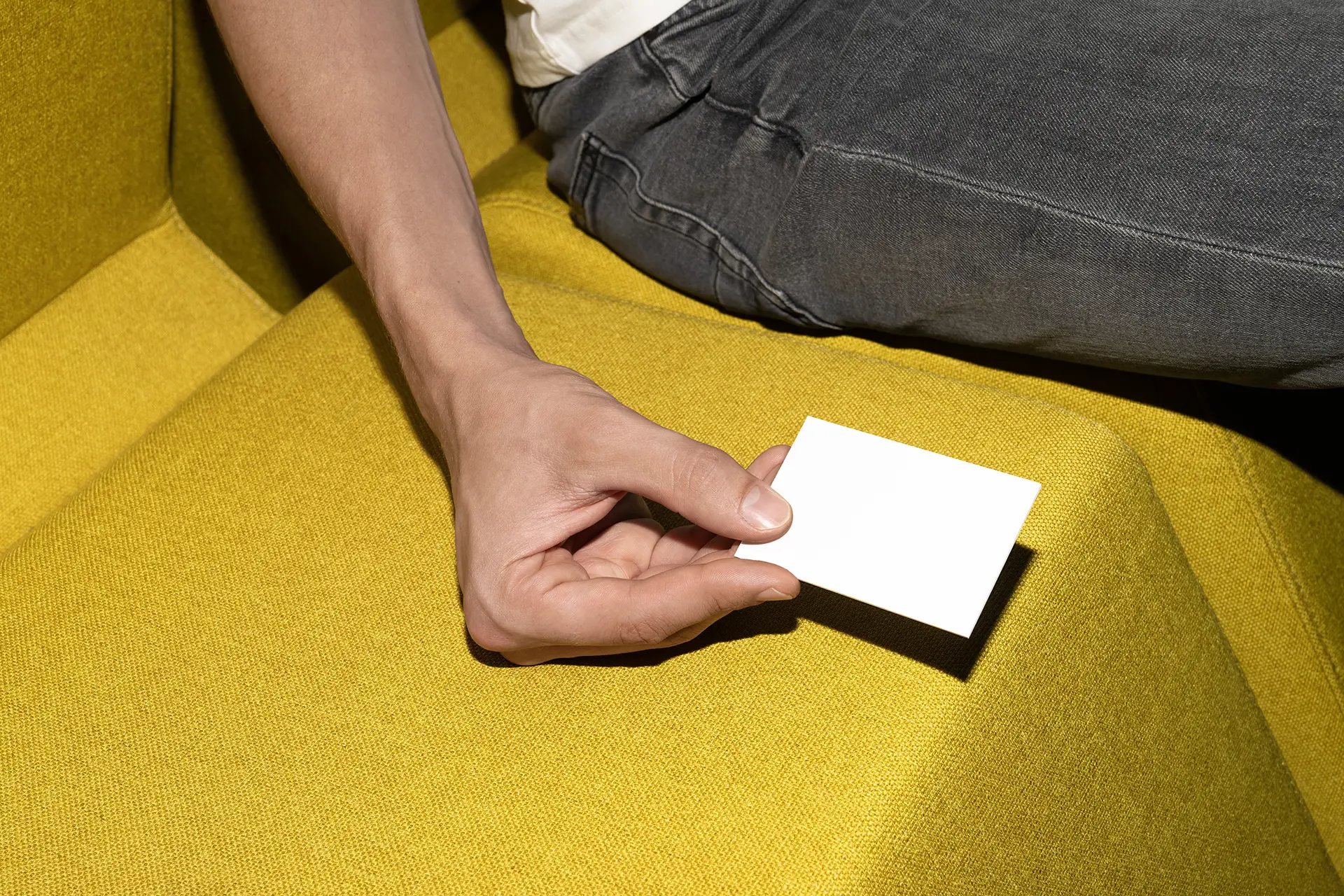 Blank Business Card Mockup held on yellow fabric seat in bright modern lighting.