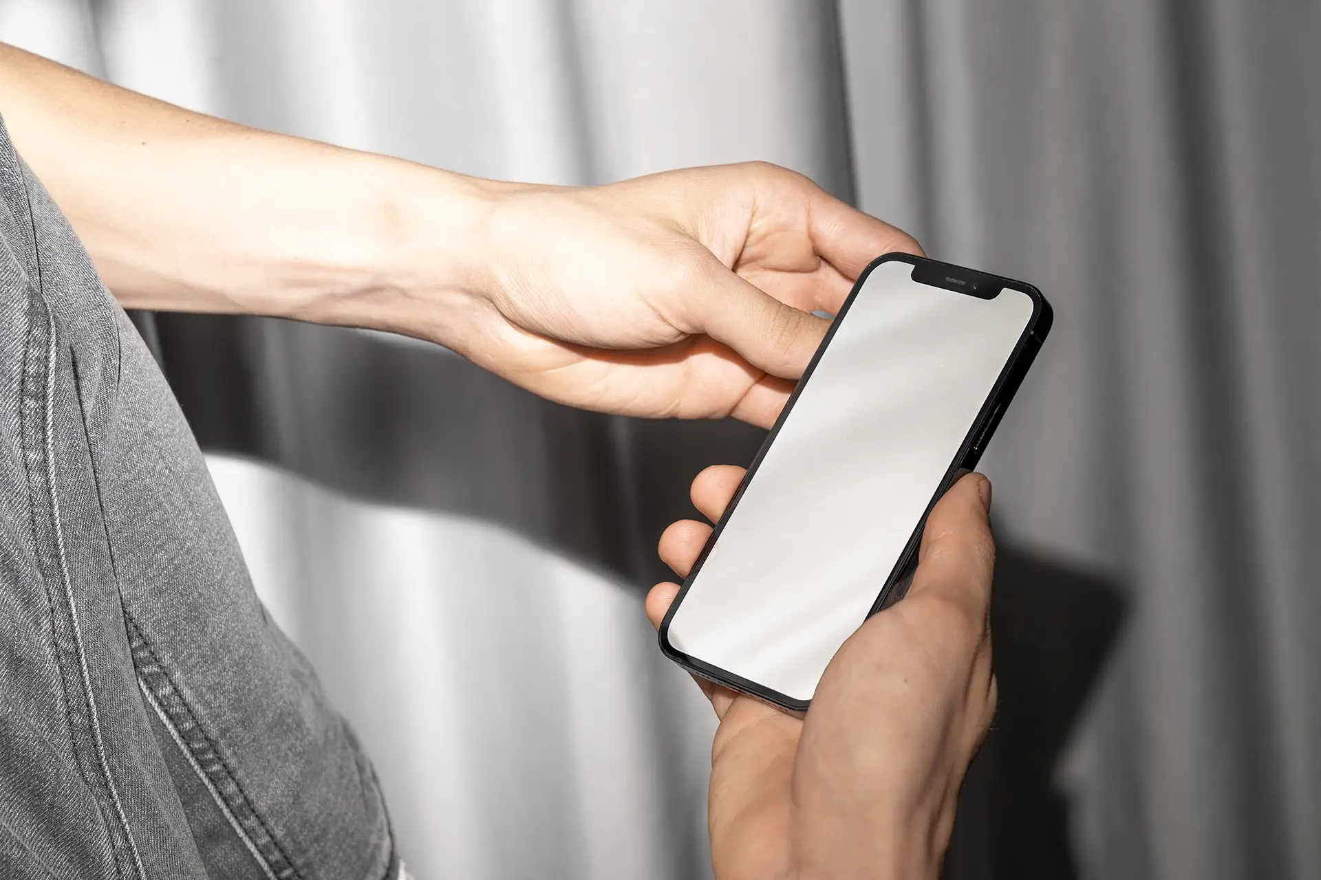 Blank iPhone Mockup photographed with flash lighting against soft grey curtain background.