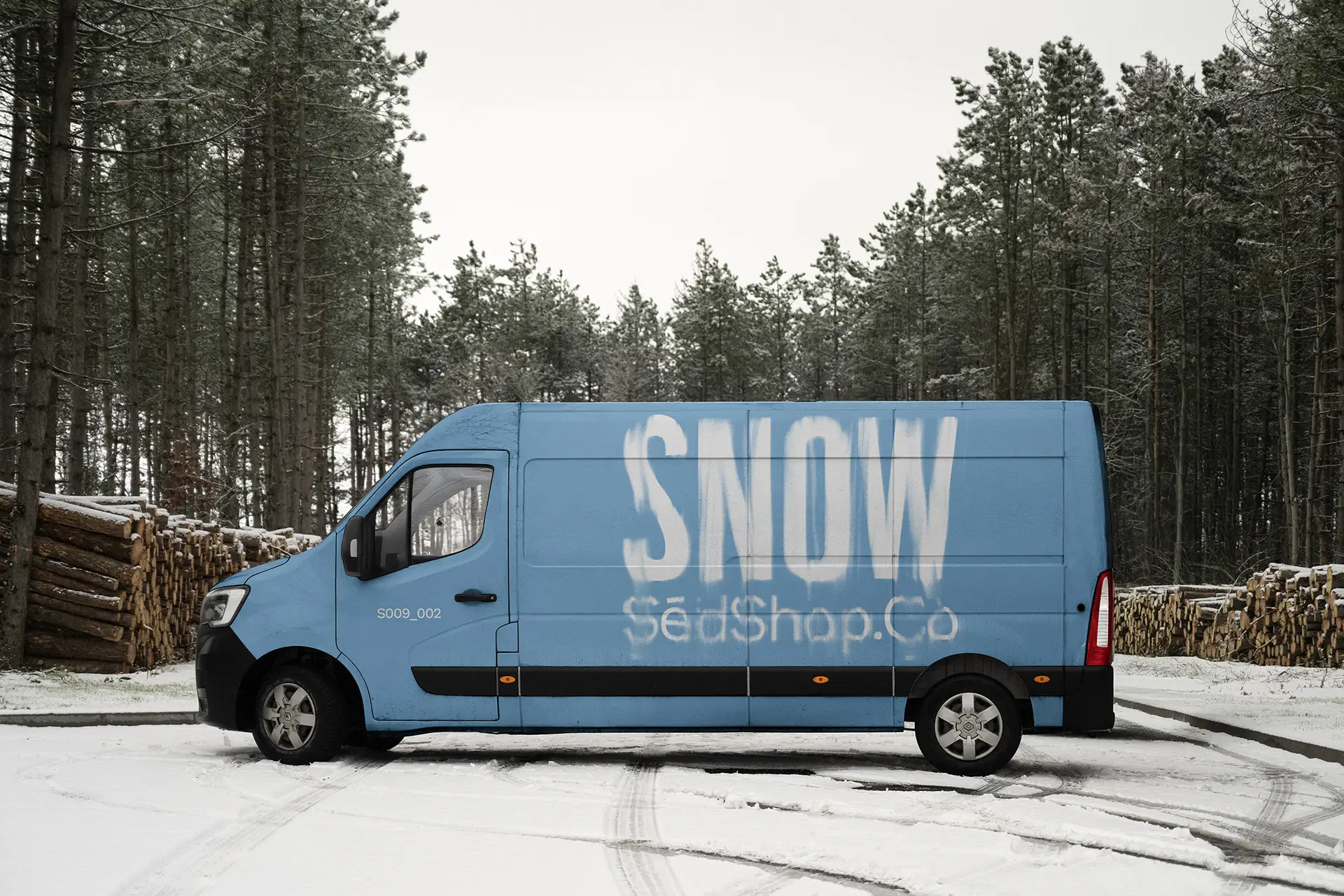 Delivery van mockup in a snowy forest setting displaying a blue winter design, photographed in soft diffused overcast light.