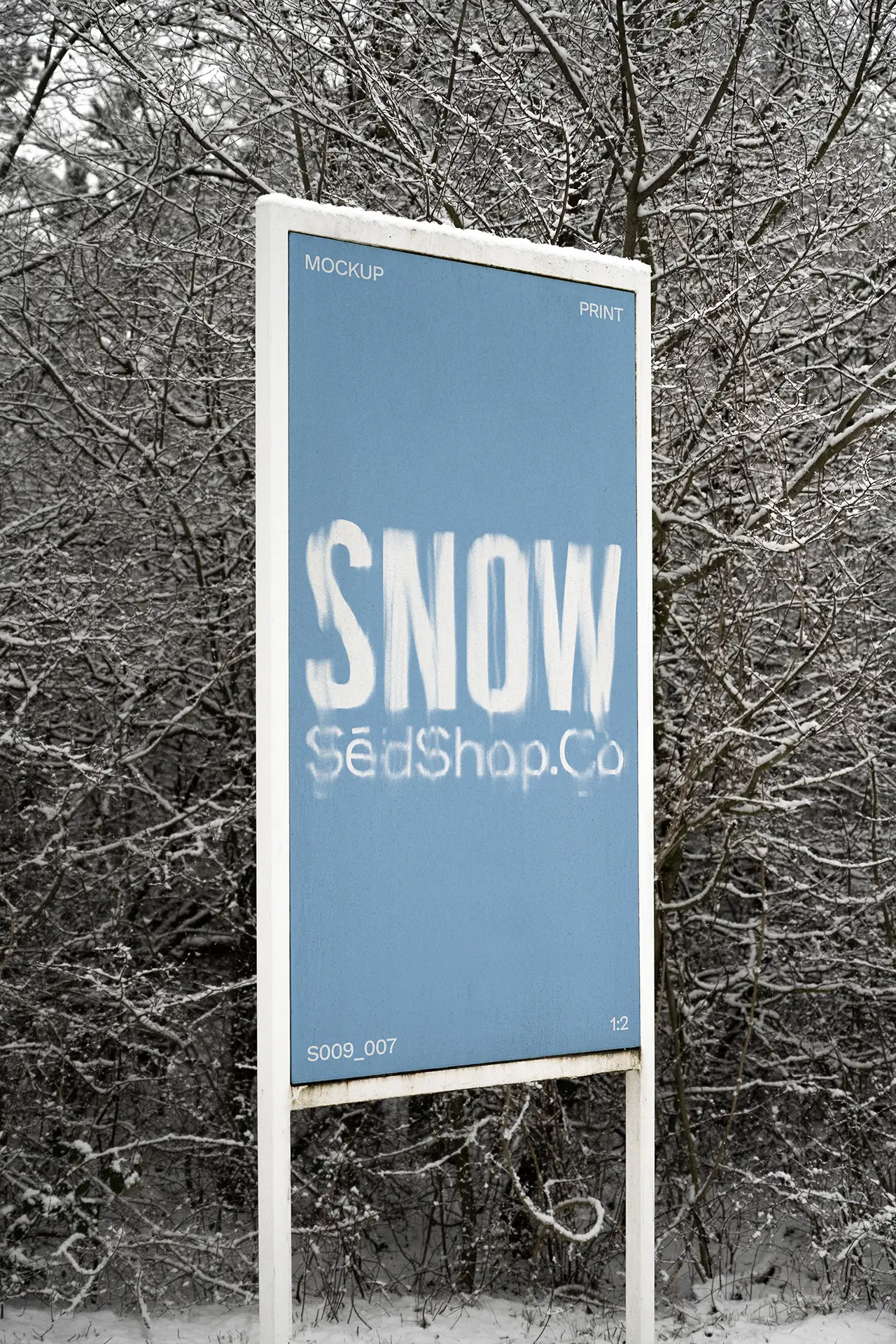 Vertical outdoor billboard mockup in a snowy forest setting displaying a blue winter design, photographed in soft diffused overcast light.