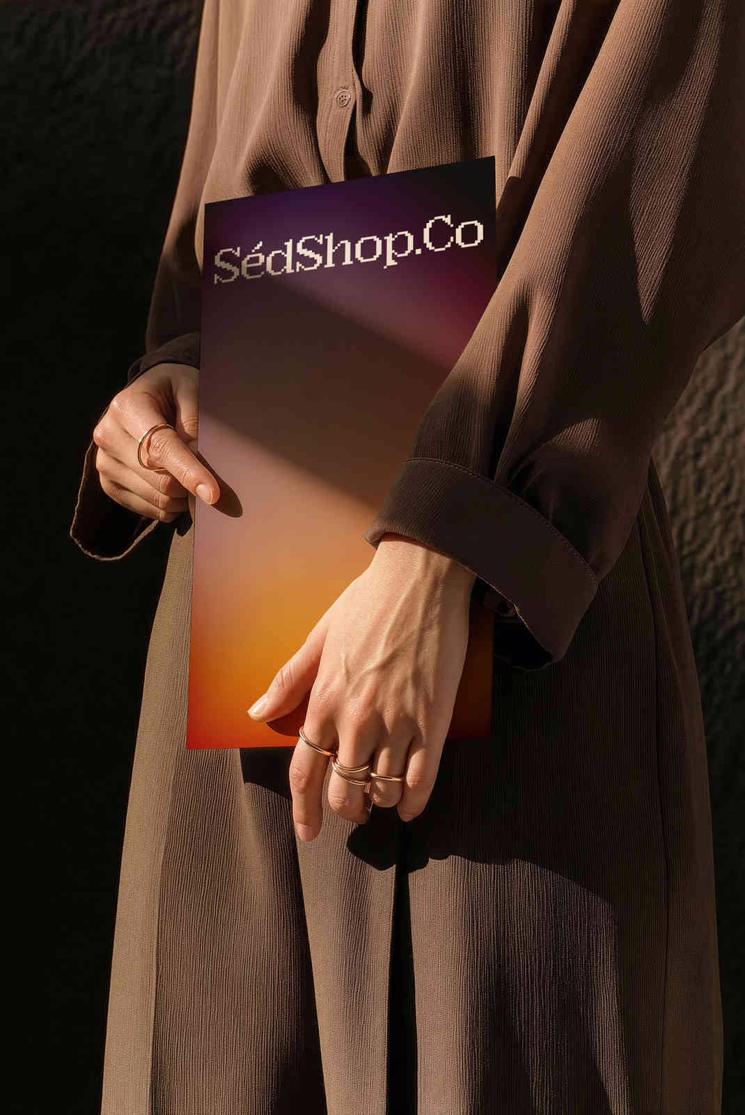 A person holding a poster print with a warm gradient design in a sunlit, tactile scene.