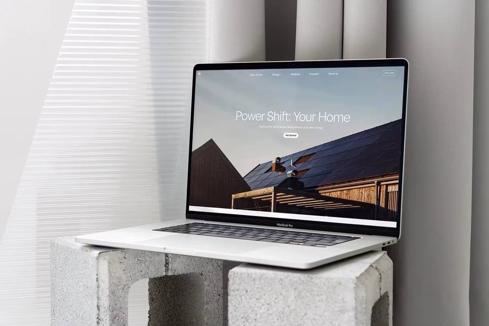 Laptop on concrete blocks showing a solar energy website mockup in a bright minimalist interior.