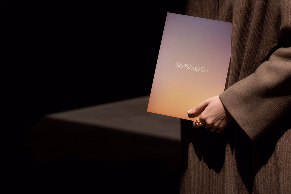 A person holding a warm gradient poster print with the SedShop.Co logo in a dark, cinematic scene.