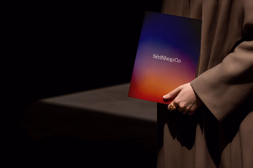 A person holding a poster print with a warm gradient design in a dark, cinematic scene.
