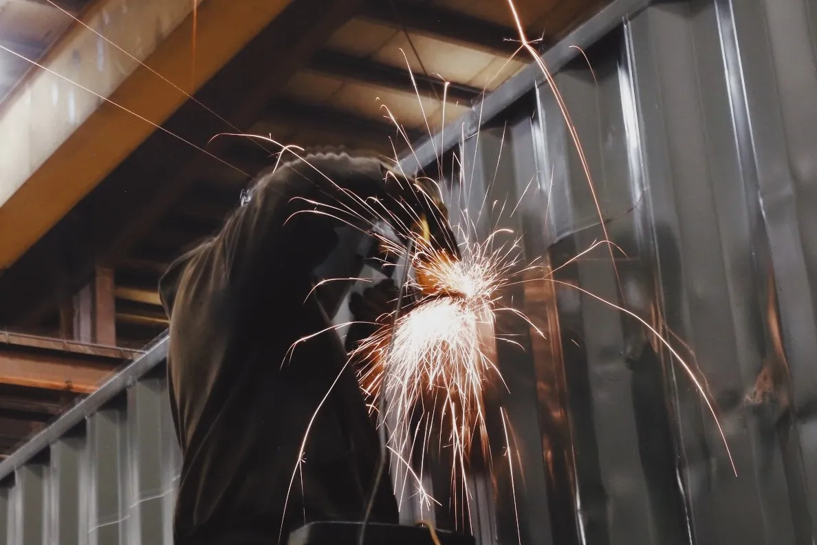 steel worker welding shipping containers