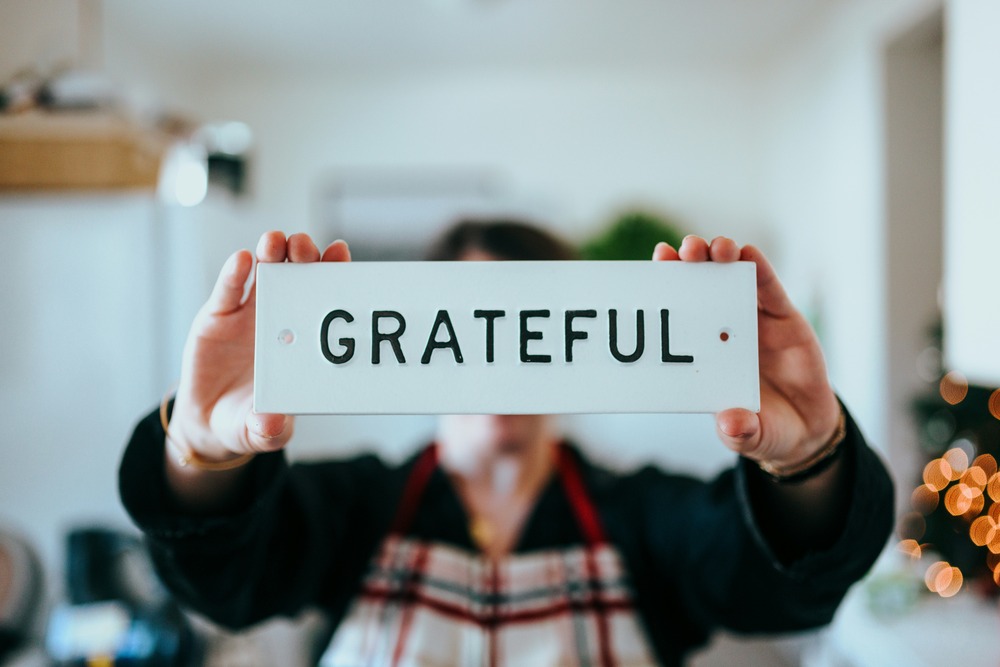 woman with apron holding sign that says "grateful"