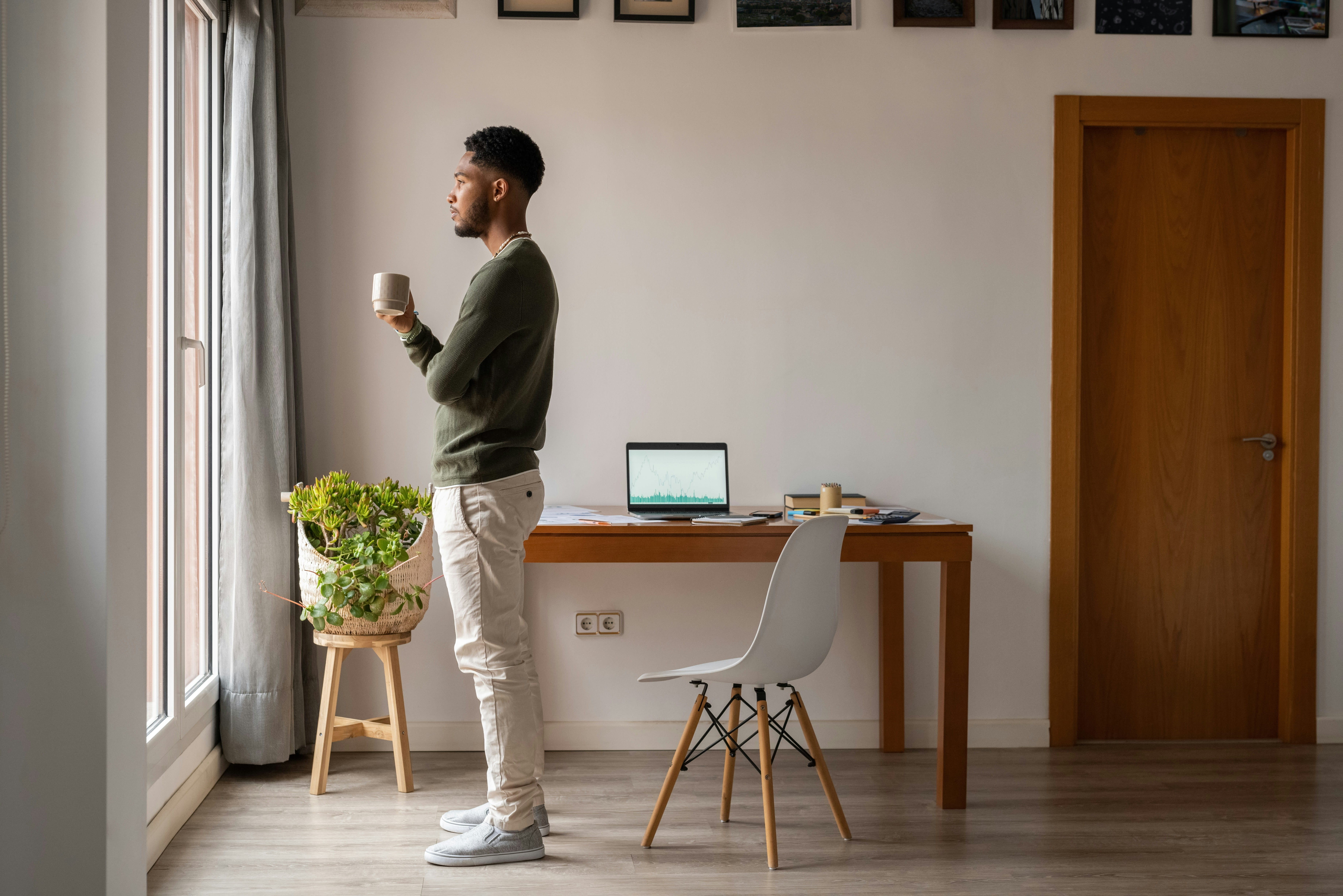 Man looking out the window holding coffee