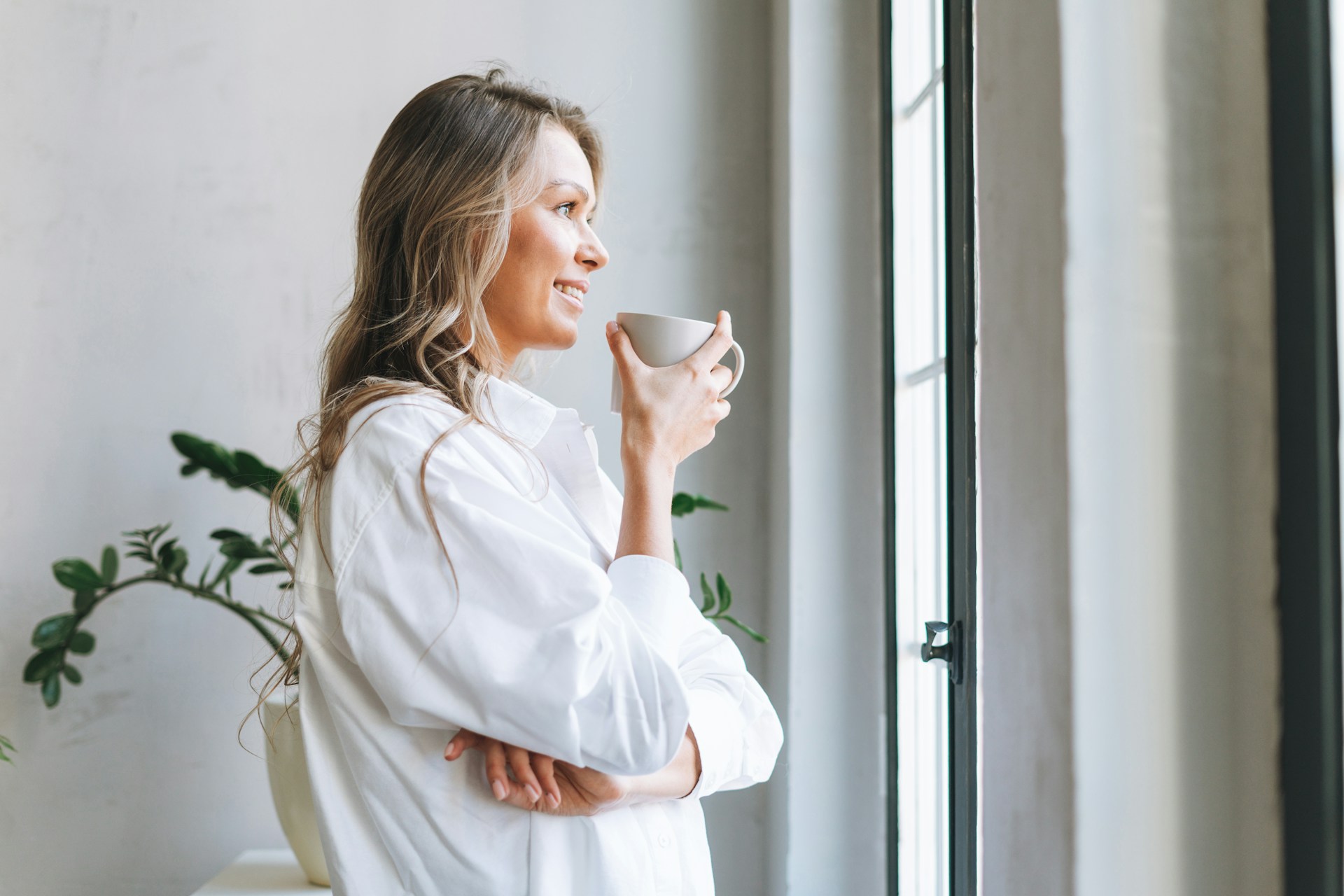 A parent enjoying a quiet cup of coffee by a window in soft morning light