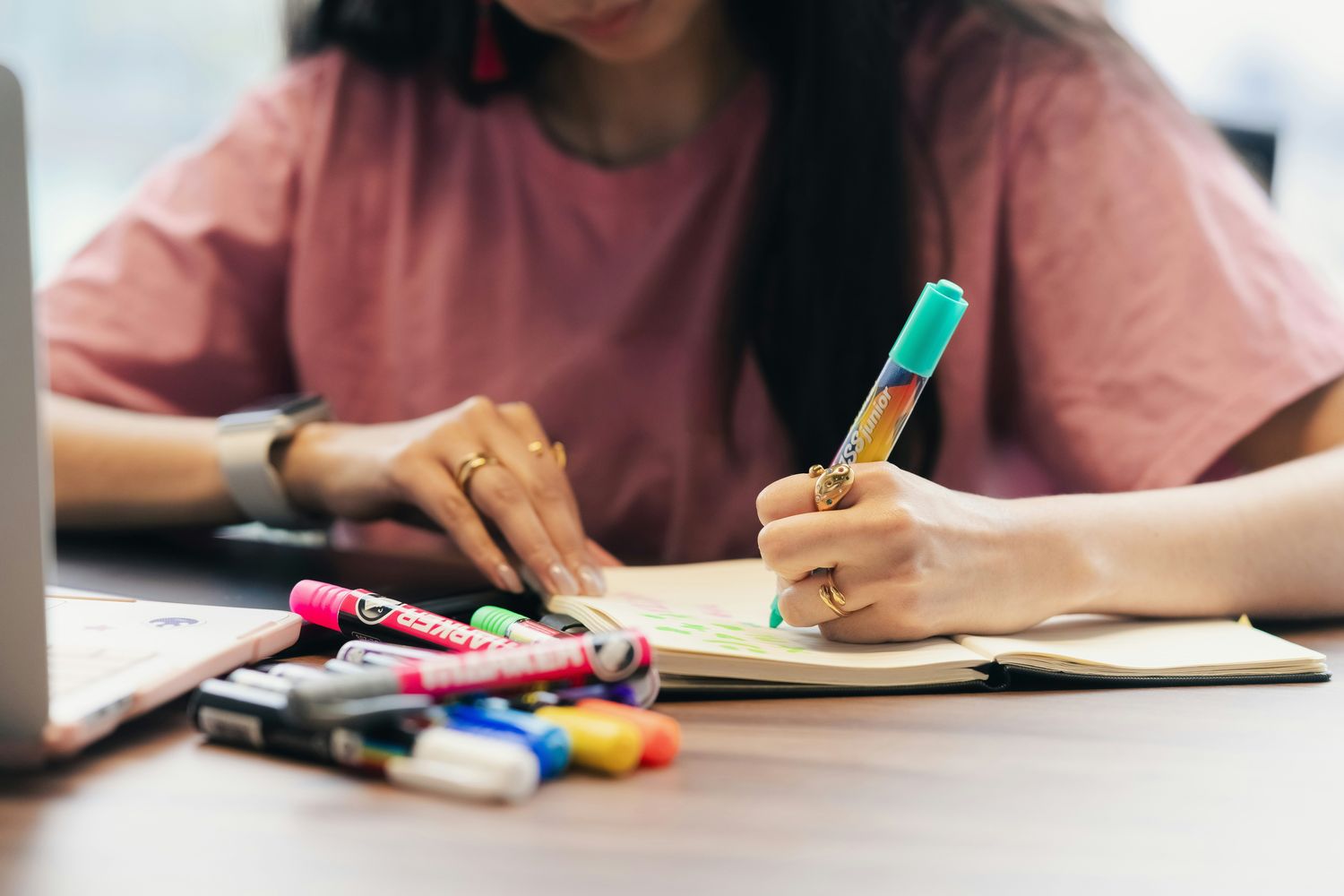 A person journaling with colorful markers at a desk.