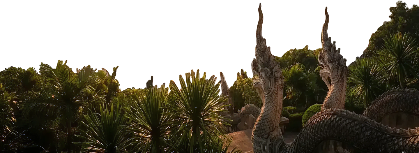 Stone serpent statues surrounded by lush green tropical plants at sunset.