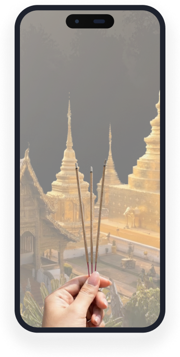 Hand holding three incense sticks with golden temple pagodas in the background under dark sky.