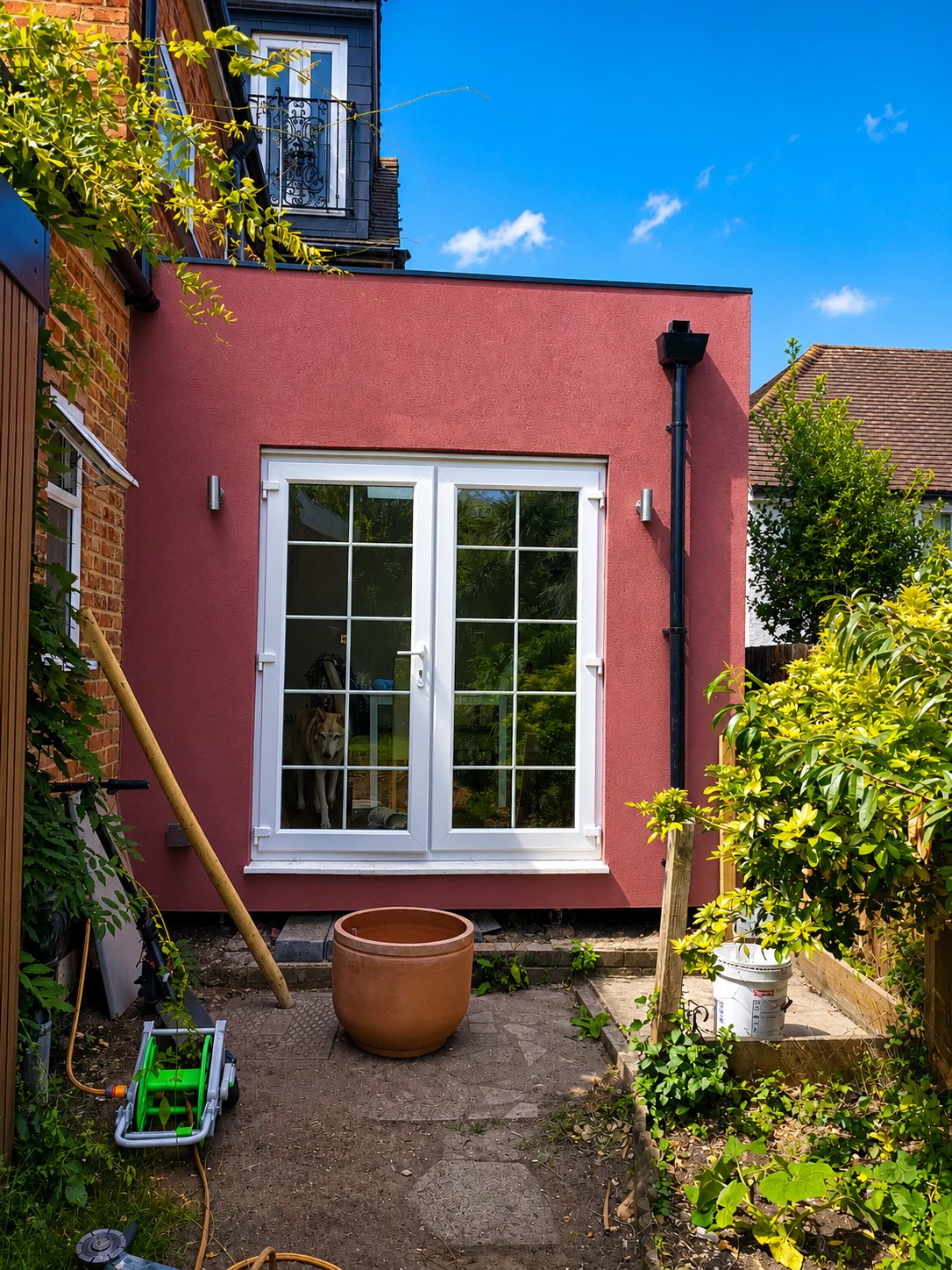 Completed single-storey rear extension in red silicone render with re-used french doors, Farnham, Surrey GU9