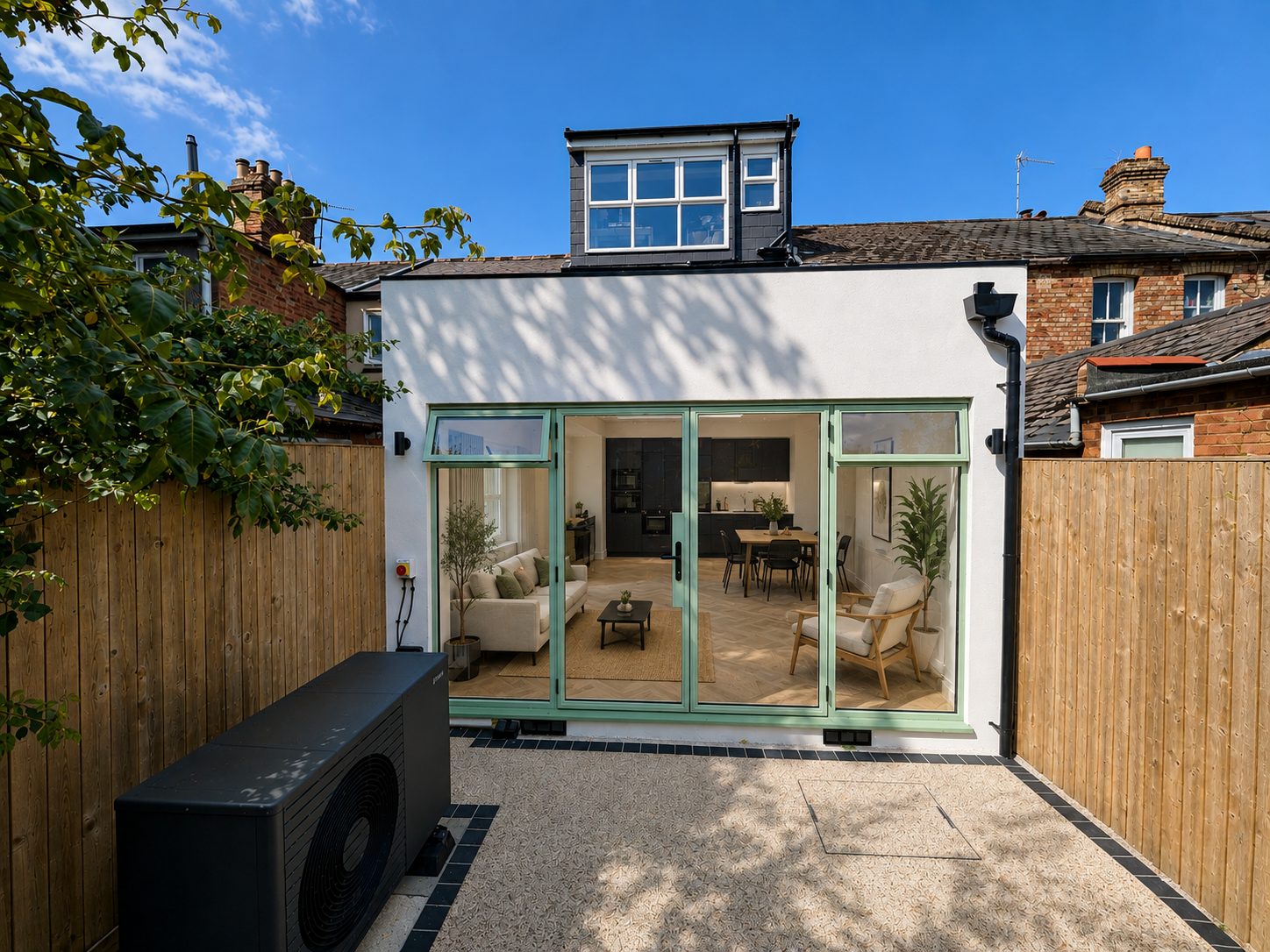 Completed single-storey rear extension in white silicone render with sage-green glazed doors and an air source heat pump, East Oxford OX4
