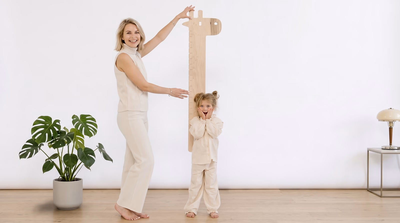 Moeder meet de lengte van haar dochter met een houten giraffe-meetlat, als beeld voor meten wat echt groeit.