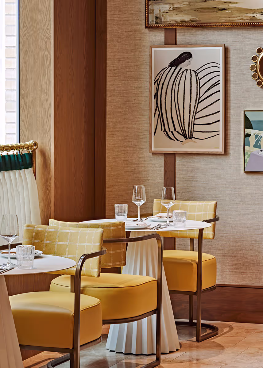 A dining room with yellow chairs and art on the wall