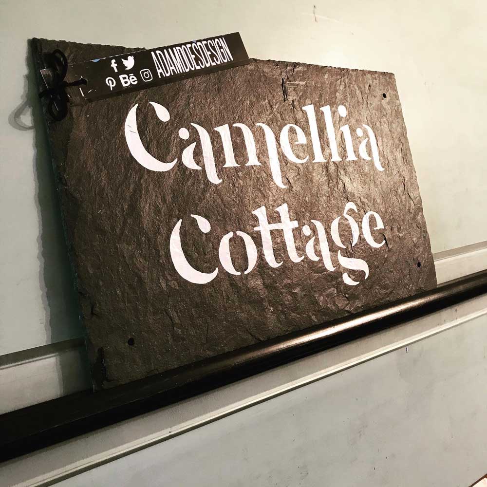 Modern hand painted house sign on a rustic slate