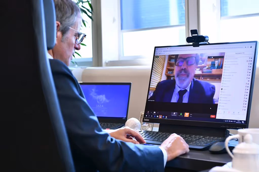 A man wearing a suit and glasses is looking at a computer screen.
