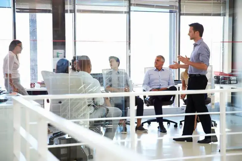 A man in a blue shirt is giving a presentation to a group of people. - UserVoice Images