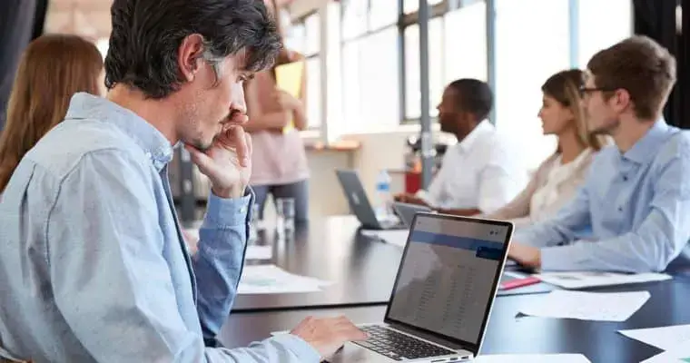 A man using a laptop in an office setting. - UserVoice Images