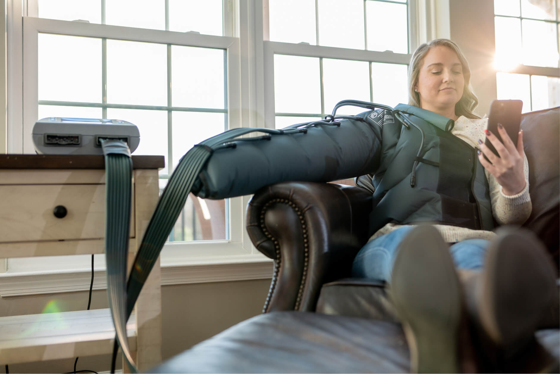 Young woman wearing the air plus compress on arm while reading a book on the couch