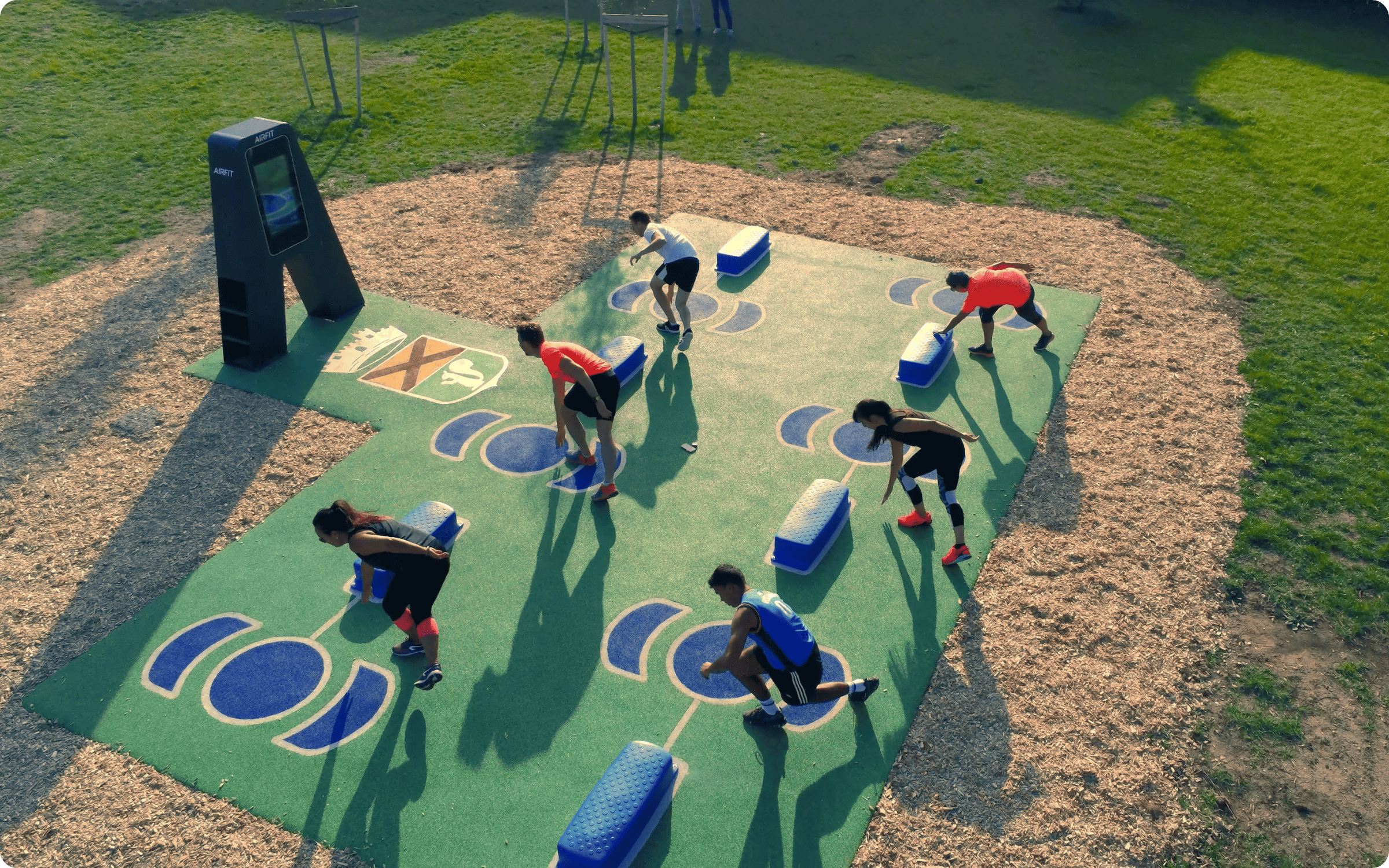 Woman in athletic wear performing a cable row exercise outdoors at a gym.