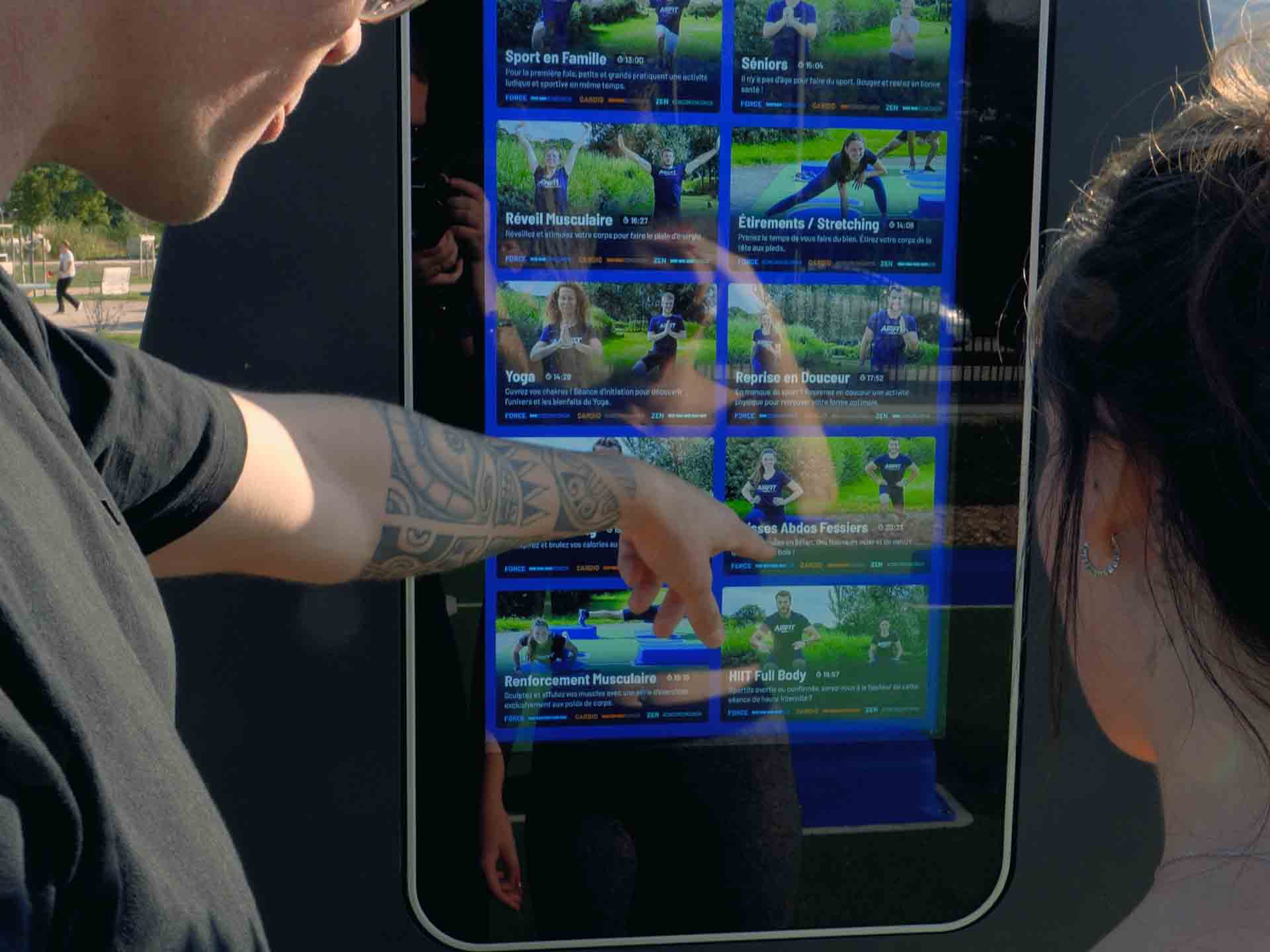 Une sportive lance sa séance sur l'écran de la station digitale AirFit à Mandelieu-la-Napoule