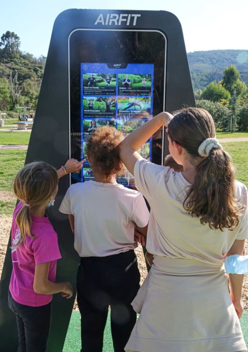 Trois enfants choisissent une séance sur l'écran tactile du totem Arena AirFit