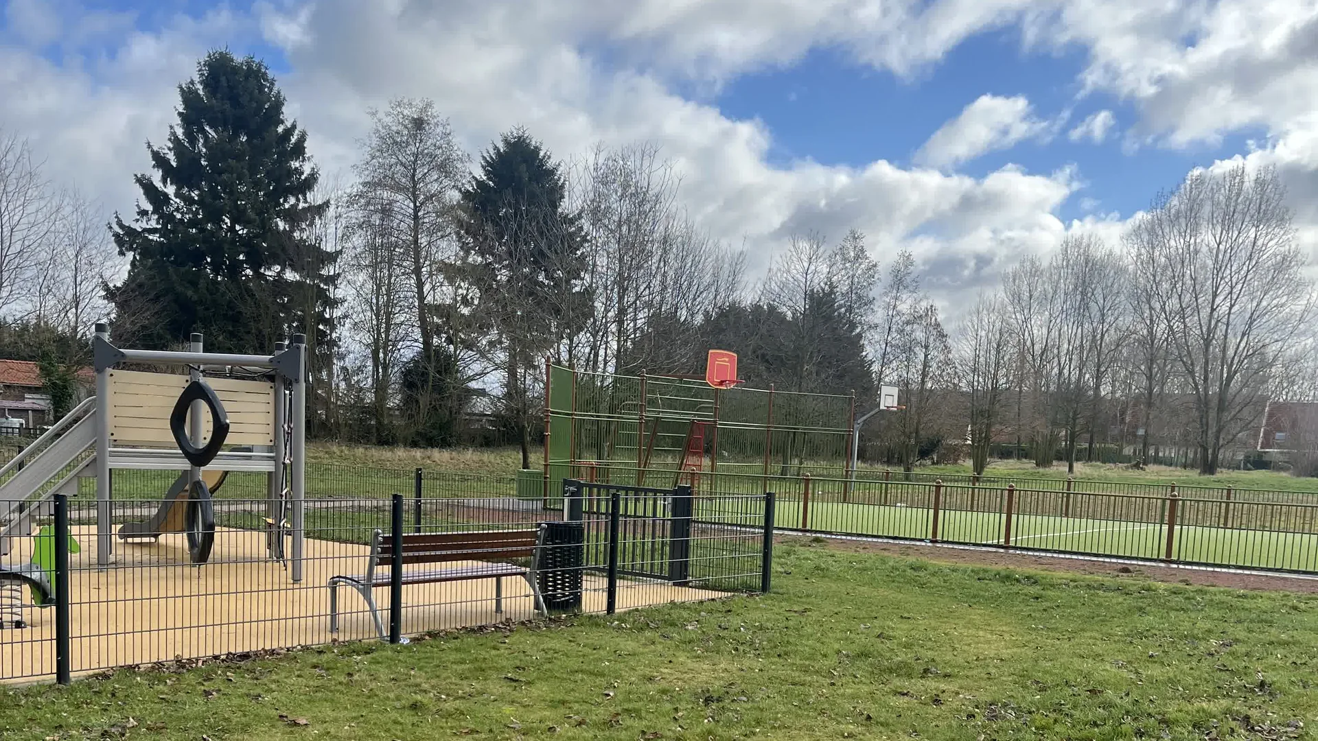 Le site du quartier des Asturies à Auby en février 2026, avant travaux : une pelouse entre l'aire de jeux et le city-stade