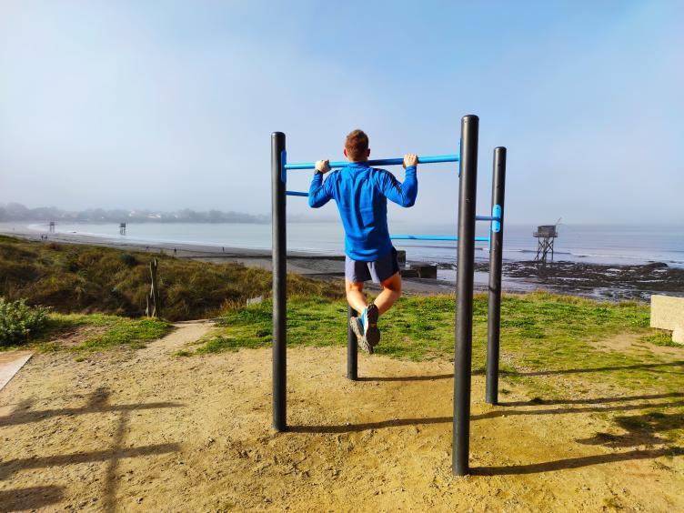 Sportif en traction sur une barre de street workout AirFit face à la mer à Saint-Michel-Chef-Chef
