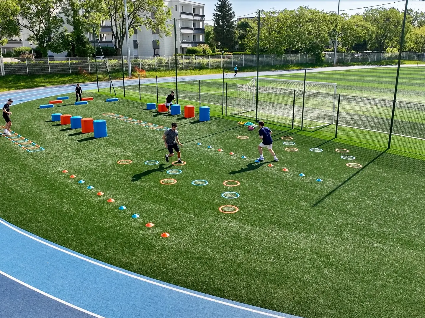 Groupe en séance sur les ateliers de motricité AirFit bleus et orange dans le virage de la piste du stade Pierre de Coubertin