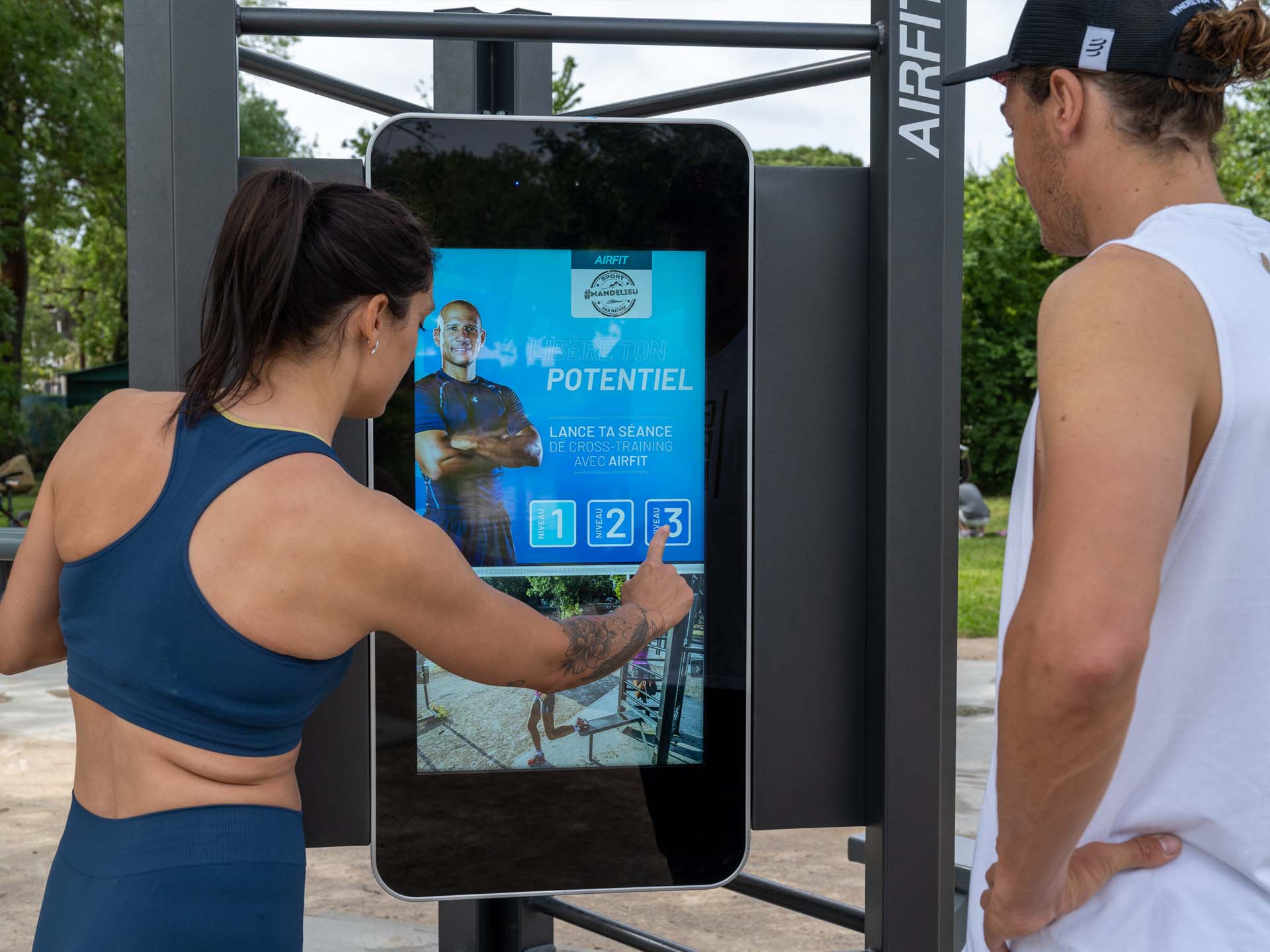 Photo d'une sportive tapant sur l'écran de la Station Digitale AirFit de Mandelieu