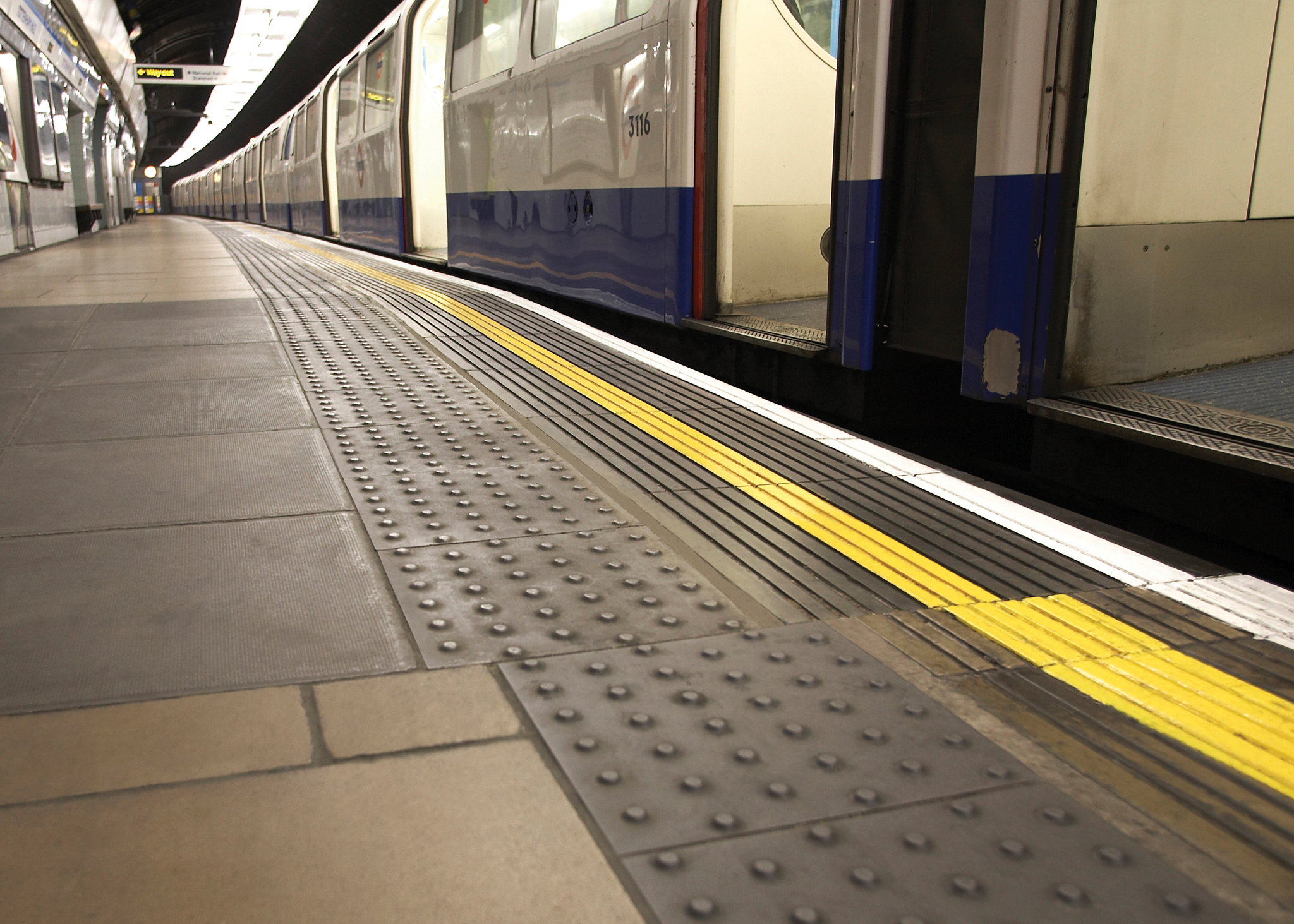Tactile paving and yellow safety line along the edge of a London Underground platform next to a stationary train