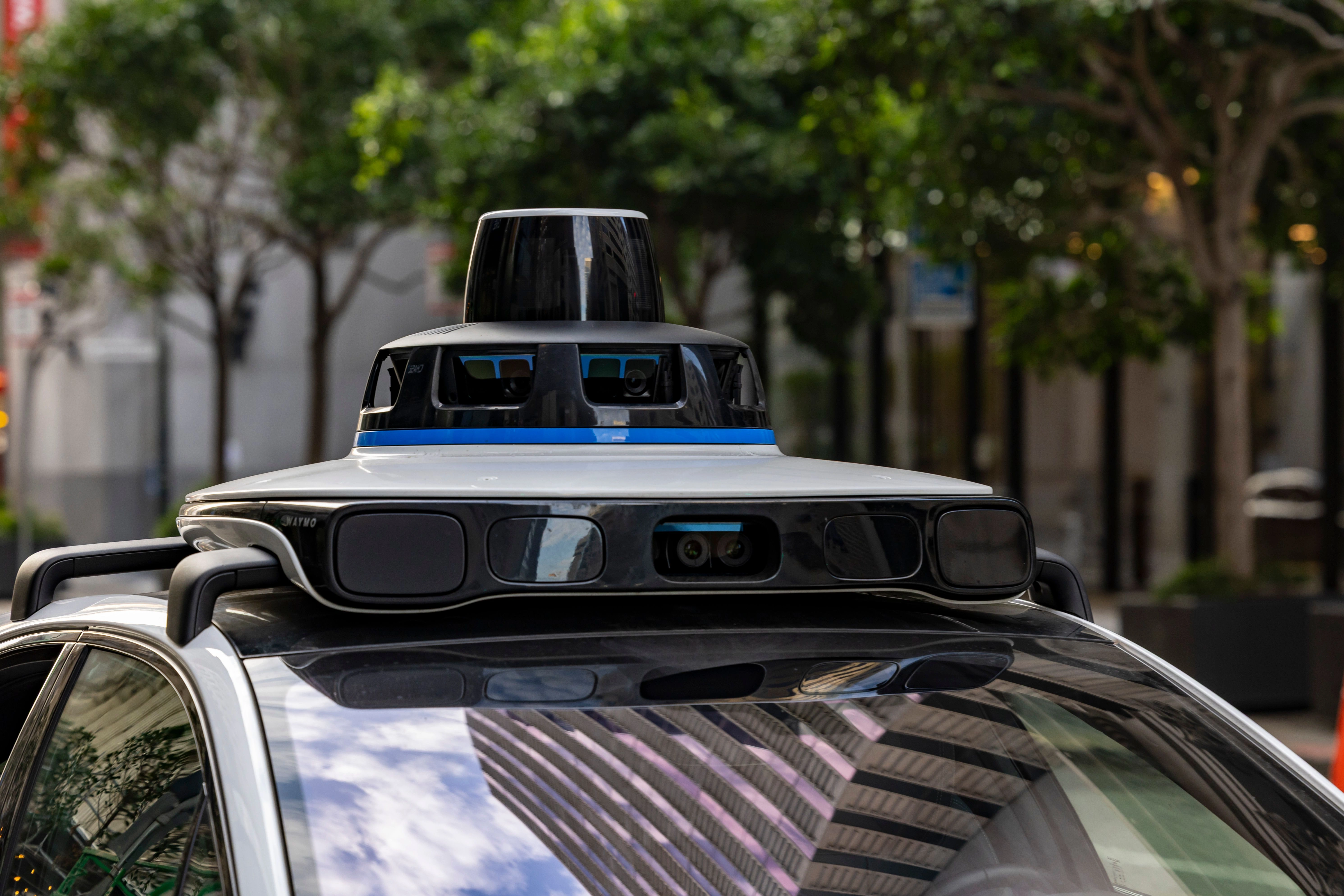 Close-up of the spinning lidar and camera unit mounted on the roof of a white self-driving car