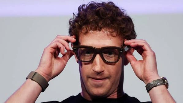 Meta chief executive Mark Zuckerberg holding a pair of Ray-Ban Meta camera glasses up to his face on stage
