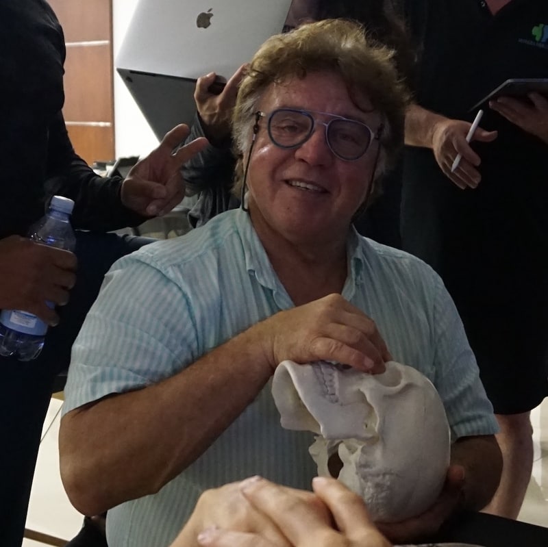 Guy VOYER, DO surrounded by students, smiling with a skull model