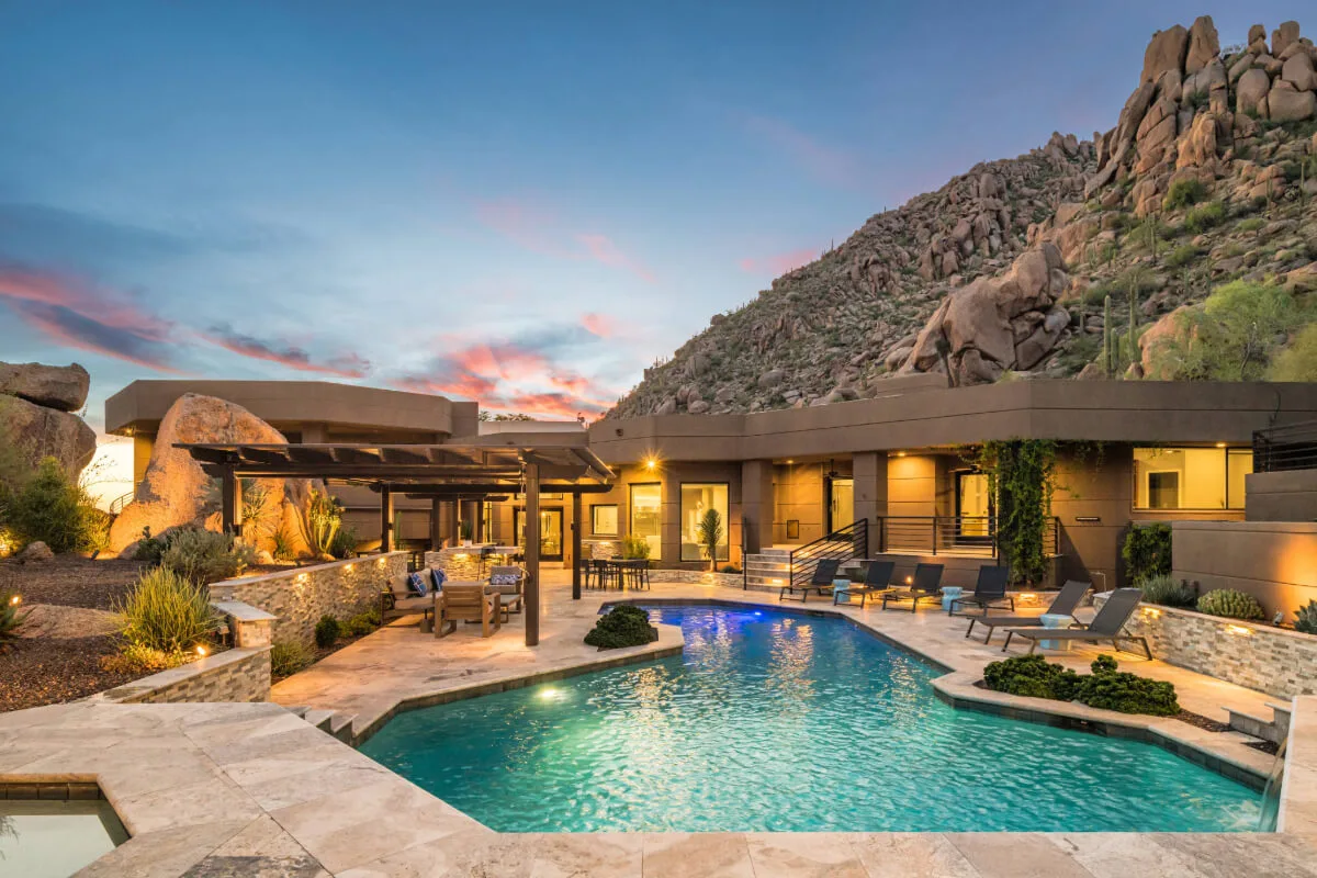 Contemporary Arizona luxury home in Scottsdale featuring geometric architectural lines, large glass windows, and ambient evening exterior lighting.