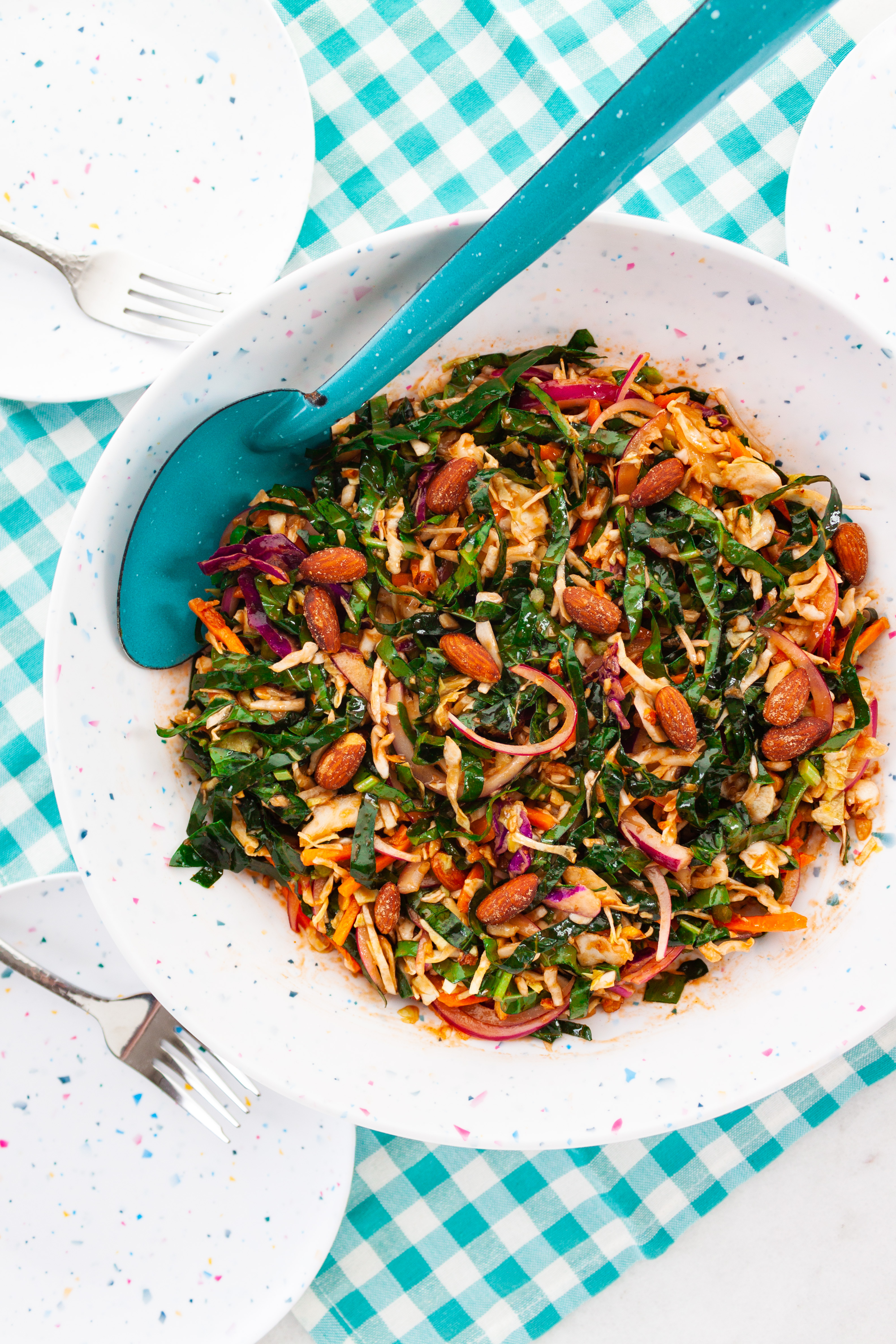 BBQ Vinaigrette Summer Slaw served in a white speckled bowl with a bright sky blue spoon