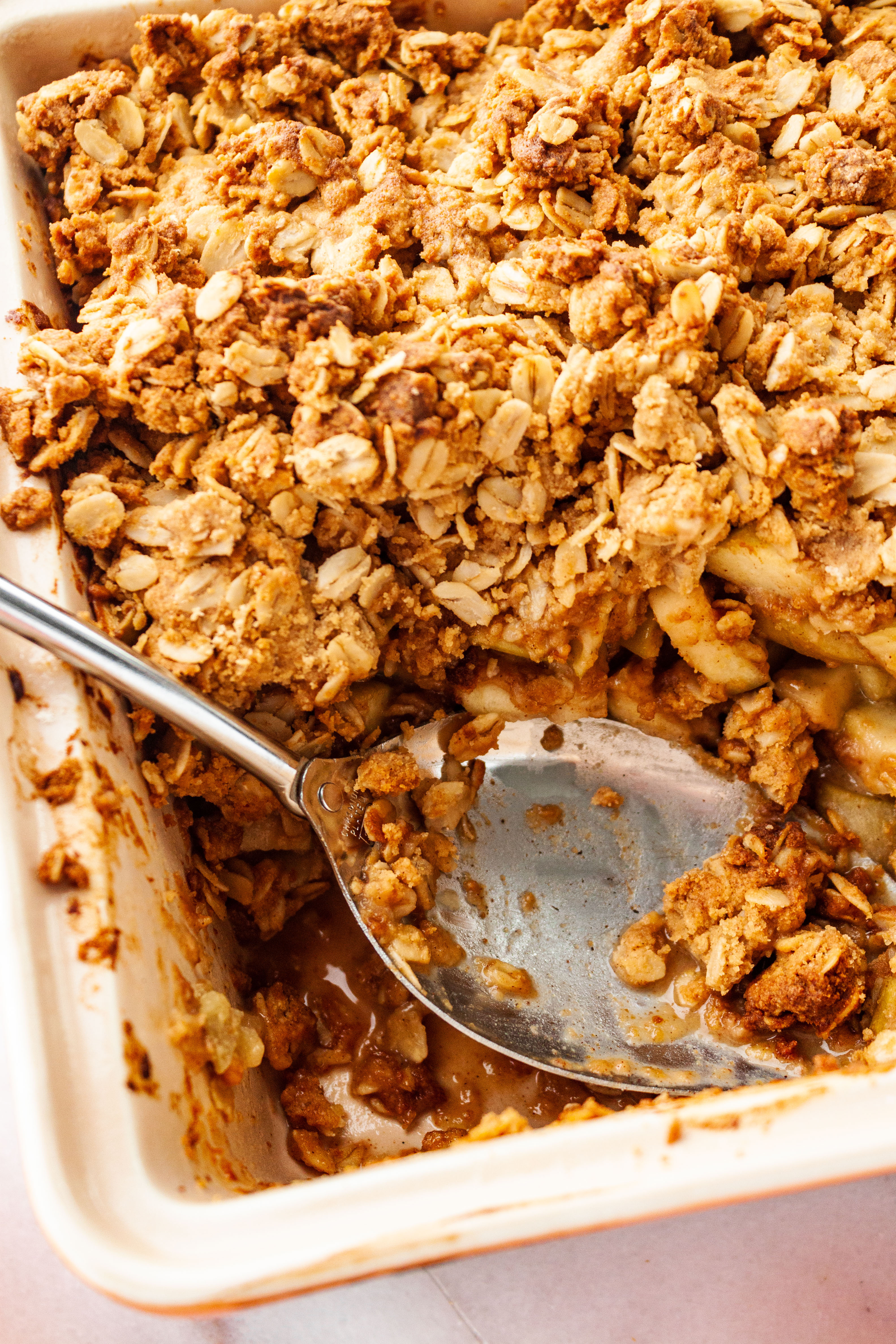 Peanut Butter Apple Crisp baked to golden brown and a serving spoon in the corner of the dish