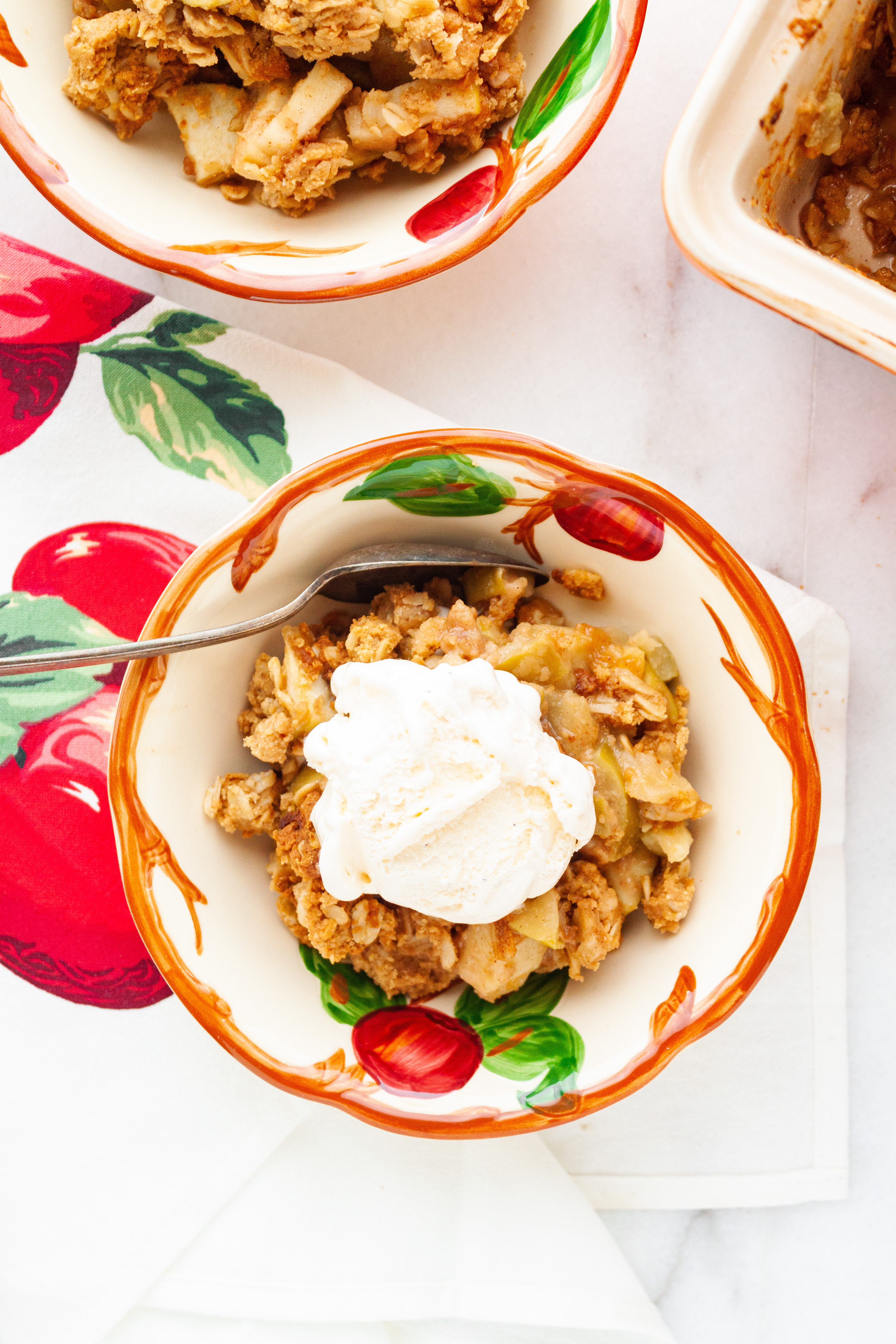 A serving of apple crisp topped with a scoop of vanilla ice cream