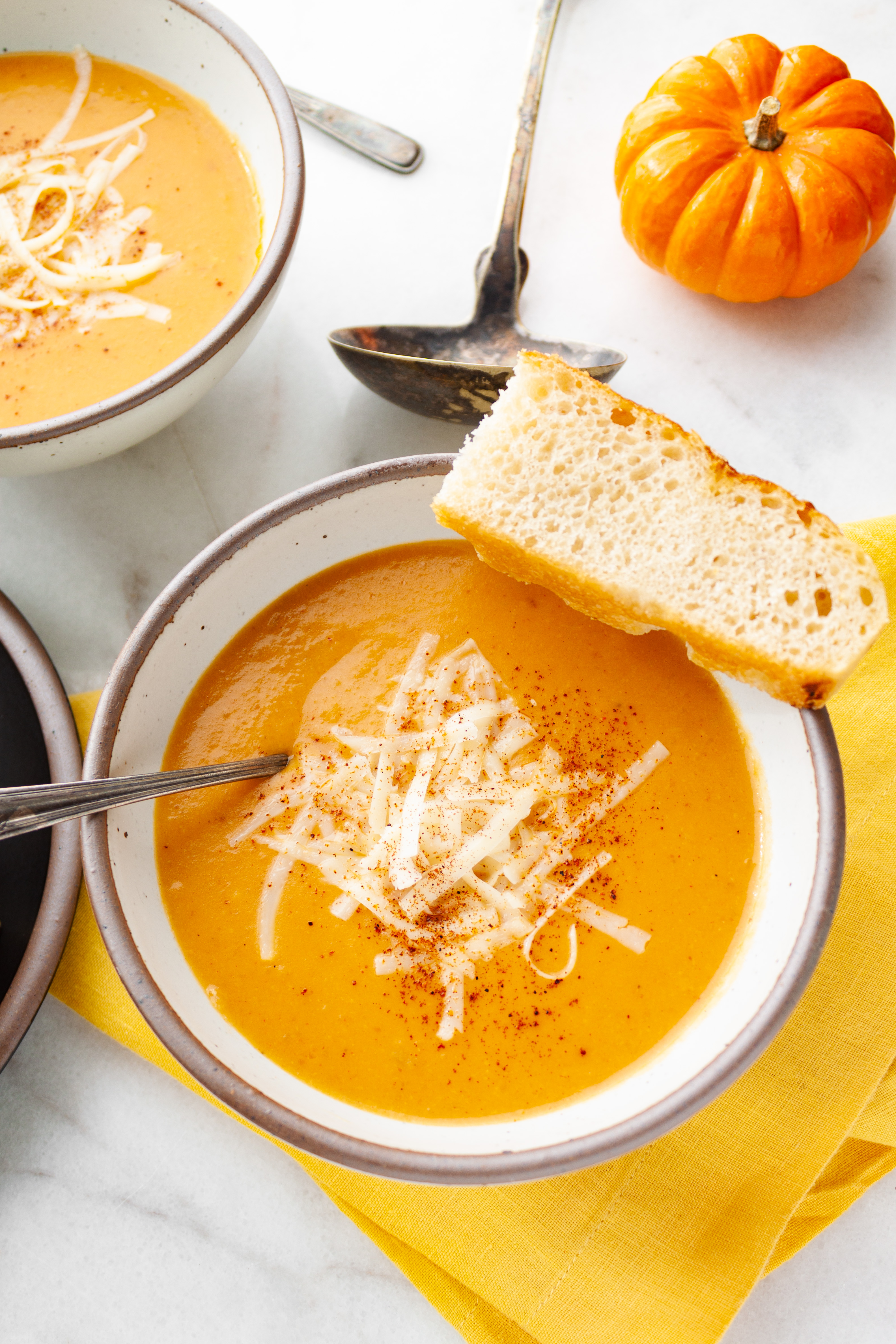 A bowl of soup with a slice of bread balanced on the edge of the bowl