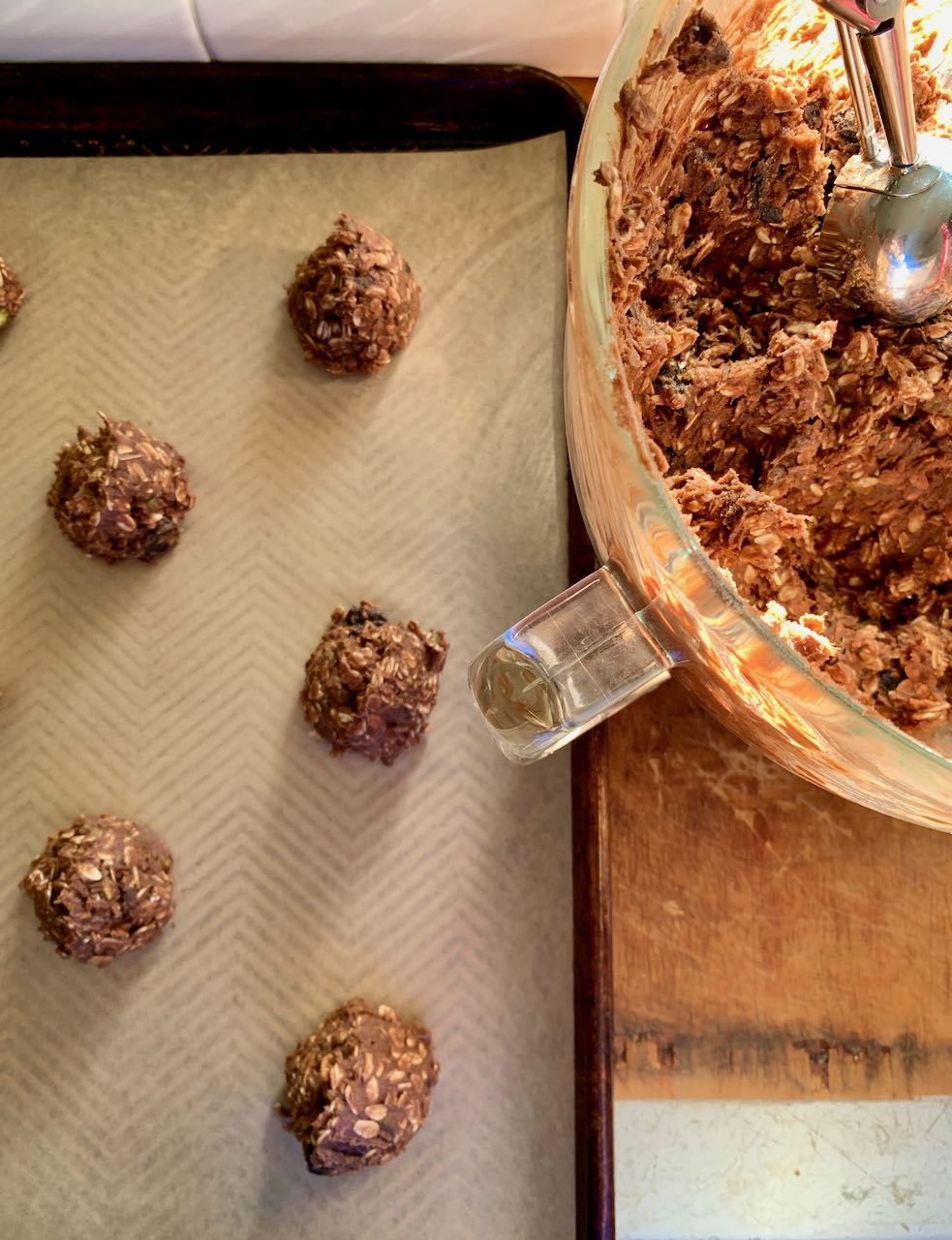 Cookie dough balls scooped onto a parchment-led baking sheet