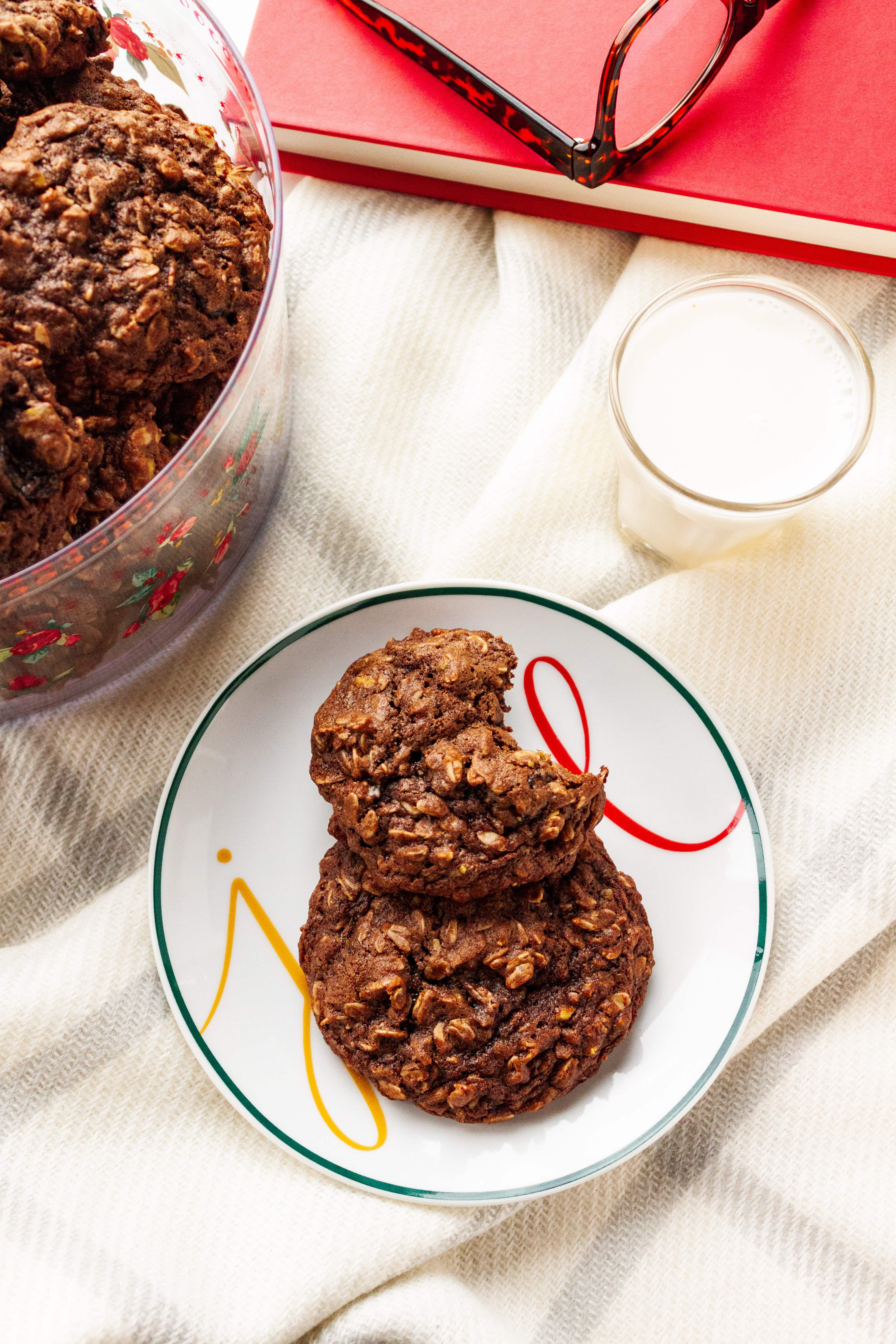 Two cookies on a plate with a glass of milk