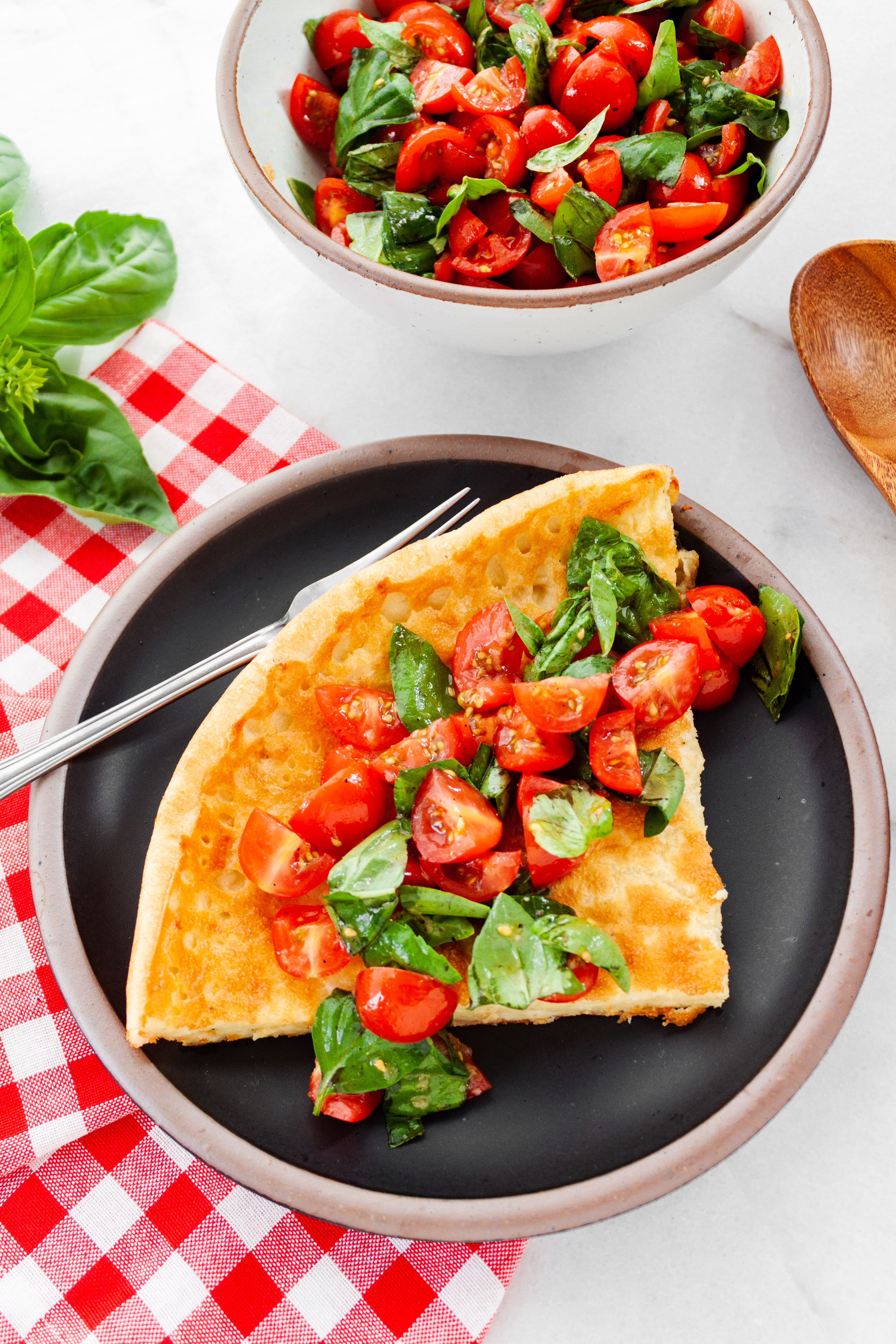 A slice of Dutch baby topped with tomato-basil mixture